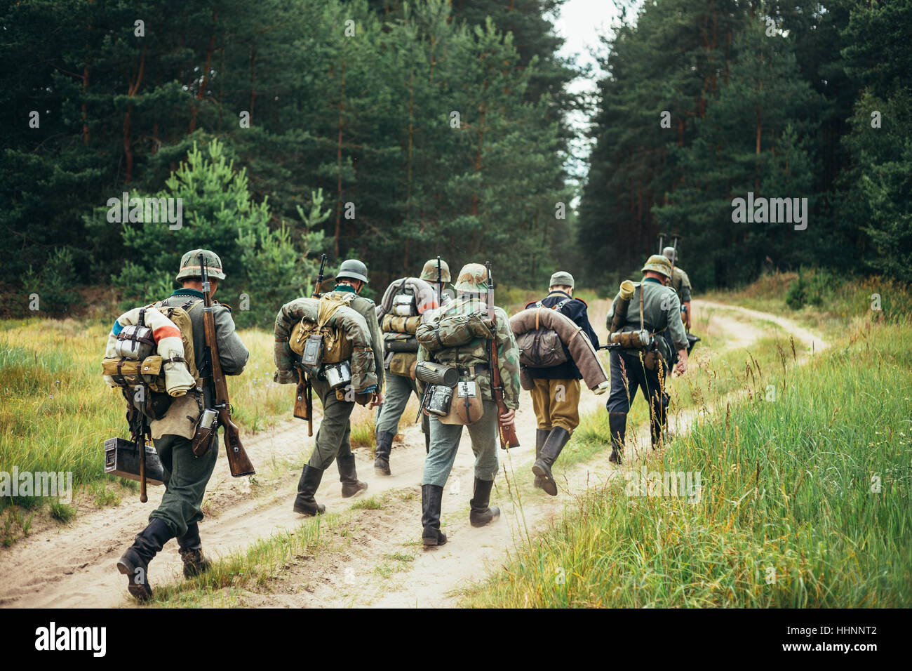 Gruppo di Unidentified Re-enactors vestiti come i soldati tedeschi in marcia lungo la strada forestale. Durante la stagione estiva. Foto Stock