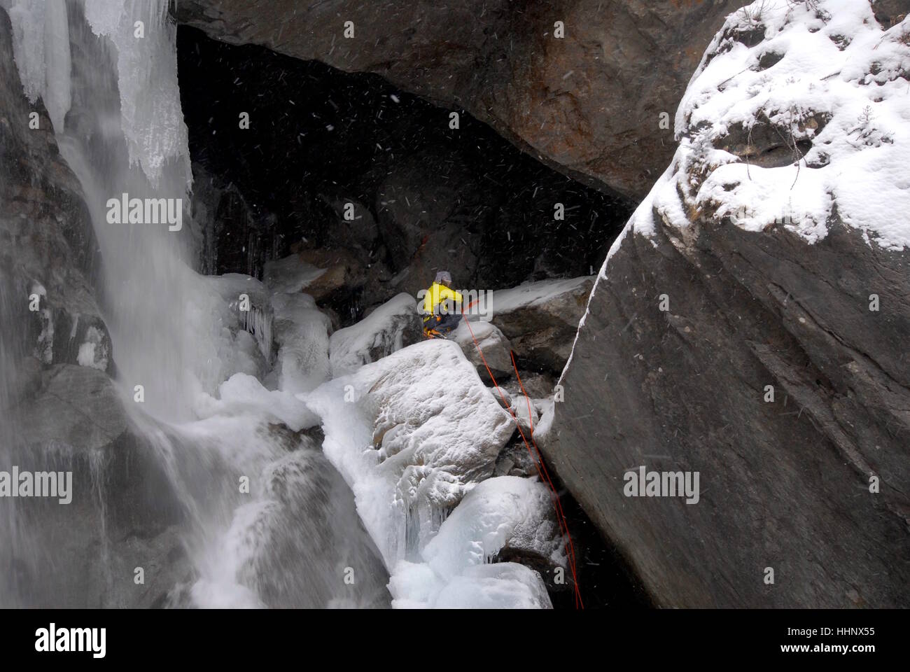 Fotografo stesso di fissaggio in posto accanto alle arrampicate su ghiaccio rotta su parzialmente congelati cascata la preparazione di fotografare gli scalatori di ghiaccio Foto Stock