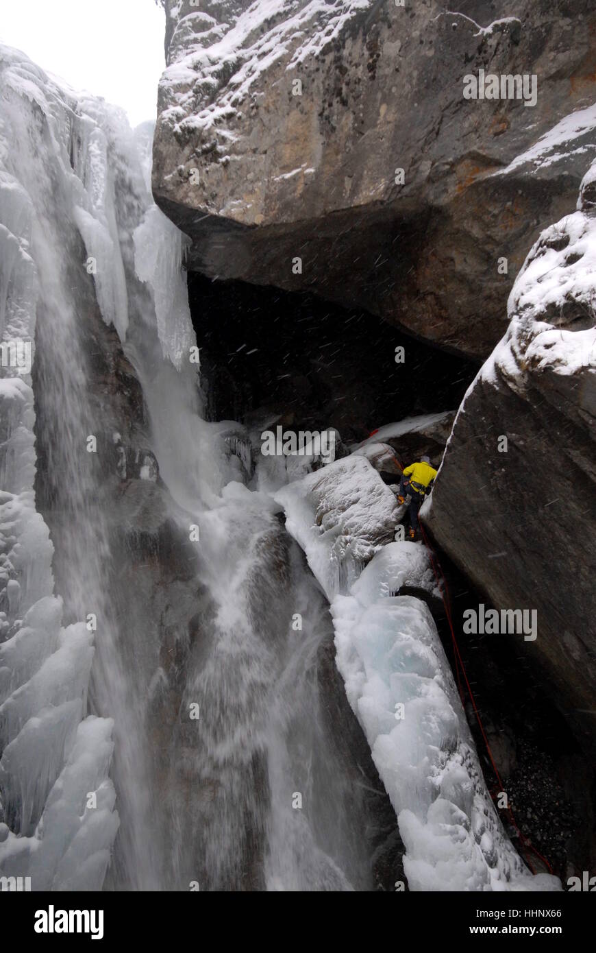 Fotografo sospesa da fisso arrampicarsi sulle funi di fissaggio stesso sul bordo di parzialmente congelati in cascata per fotografare gli alpinisti sul ghiaccio Foto Stock