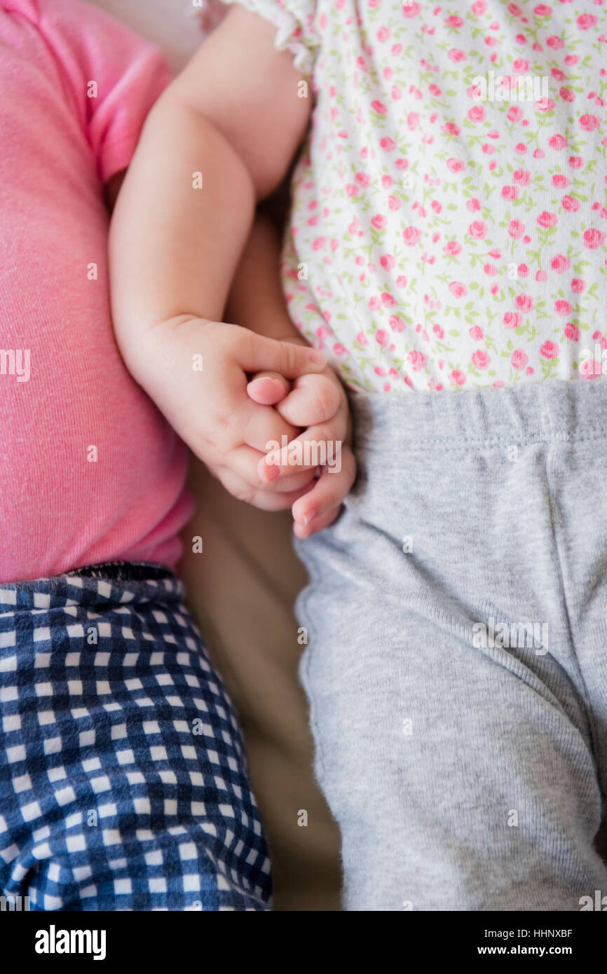 Twin caucasica baby ragazze tenendo le mani Foto Stock