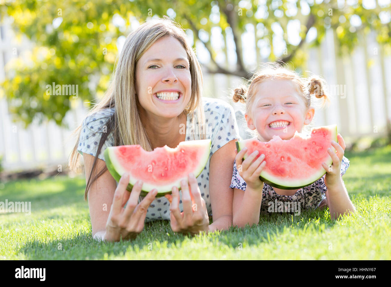 Caucasian madre e figlia in posa erba mangiando anguria Foto Stock