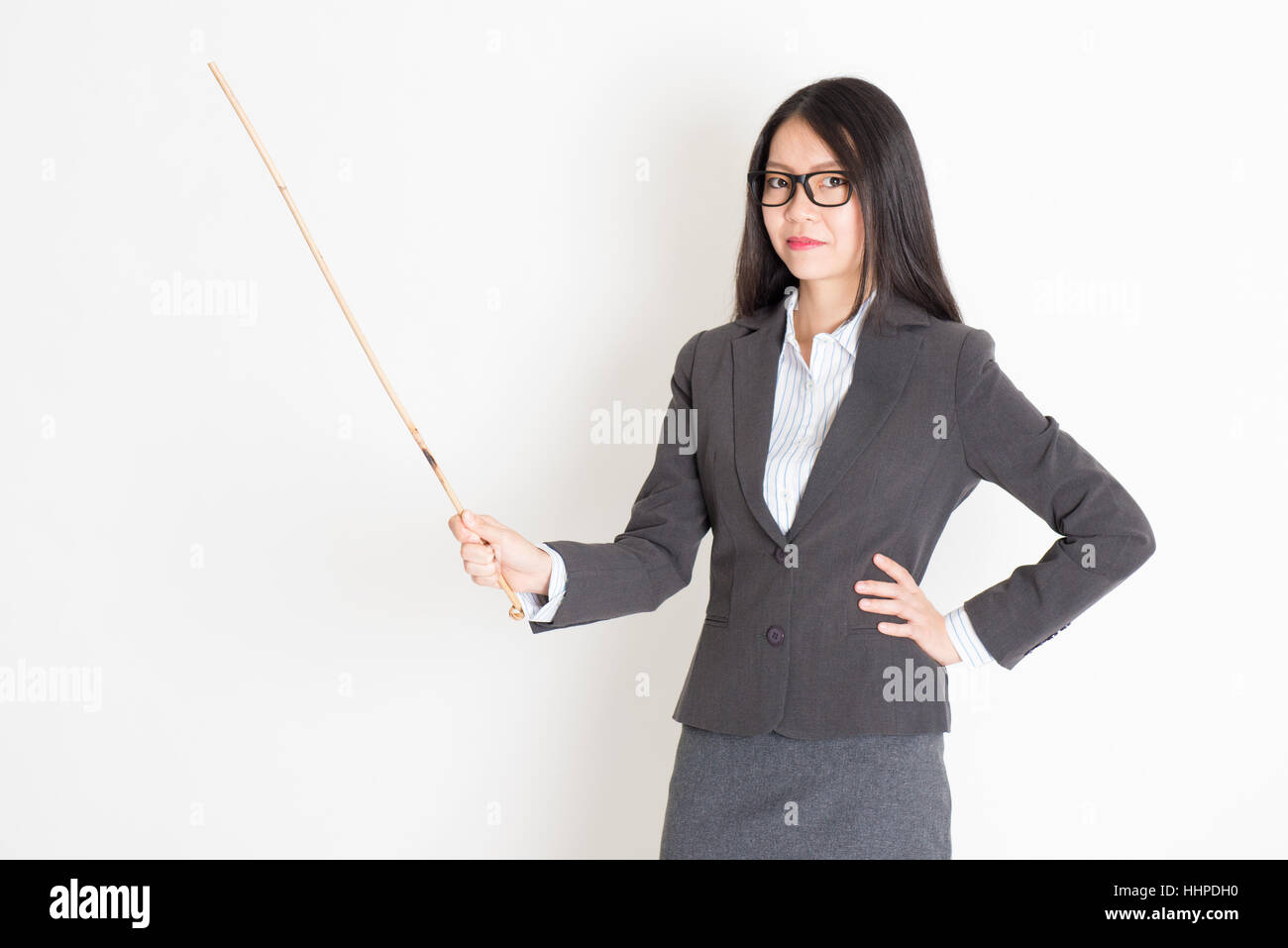 Asian insegnante femmina mano che tiene una canna nella classe lezione permanente sulla pianura dello sfondo. Foto Stock