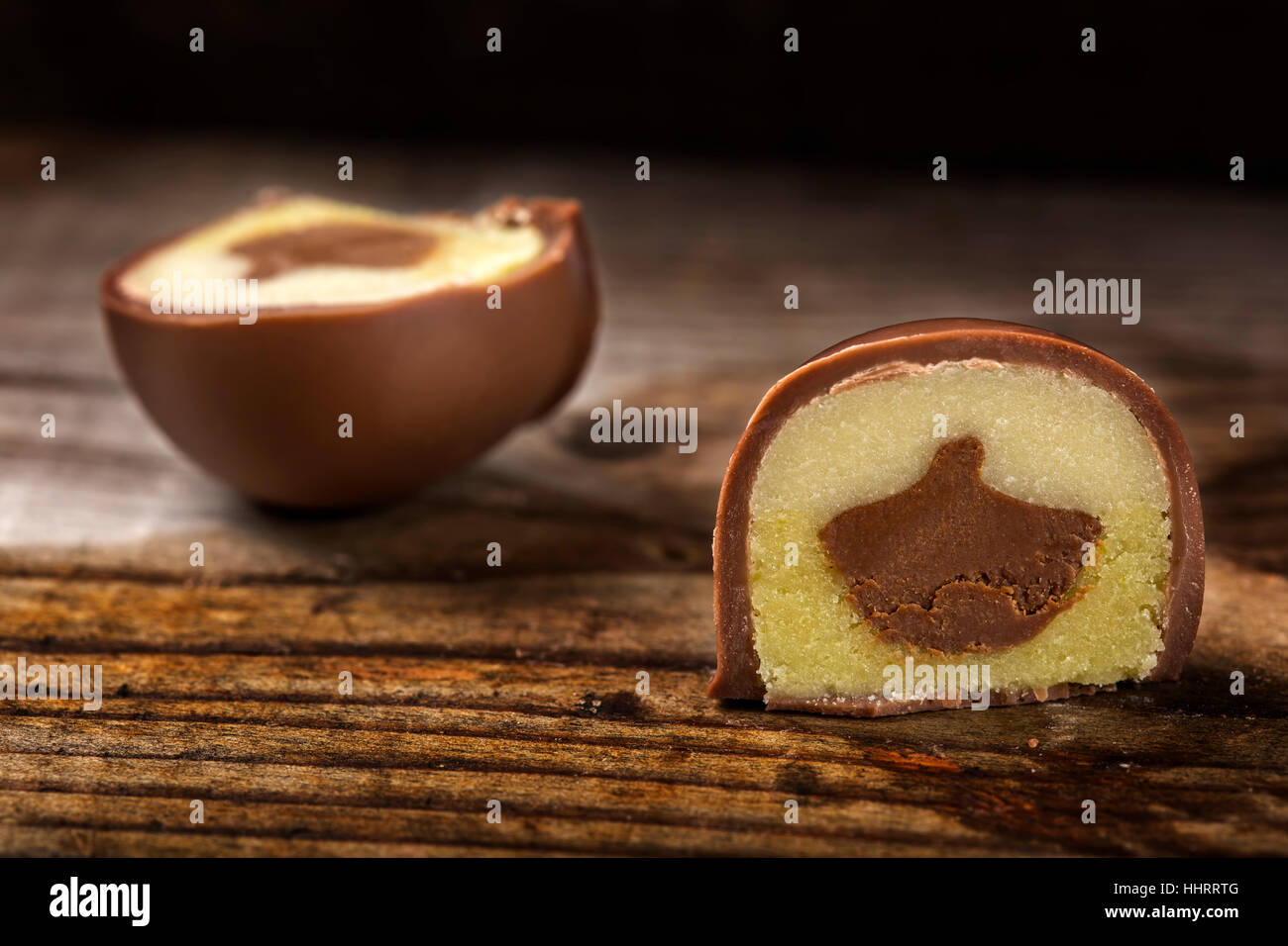Un round caramella di cioccolato tagliato a metà su sfondo di legno Foto Stock