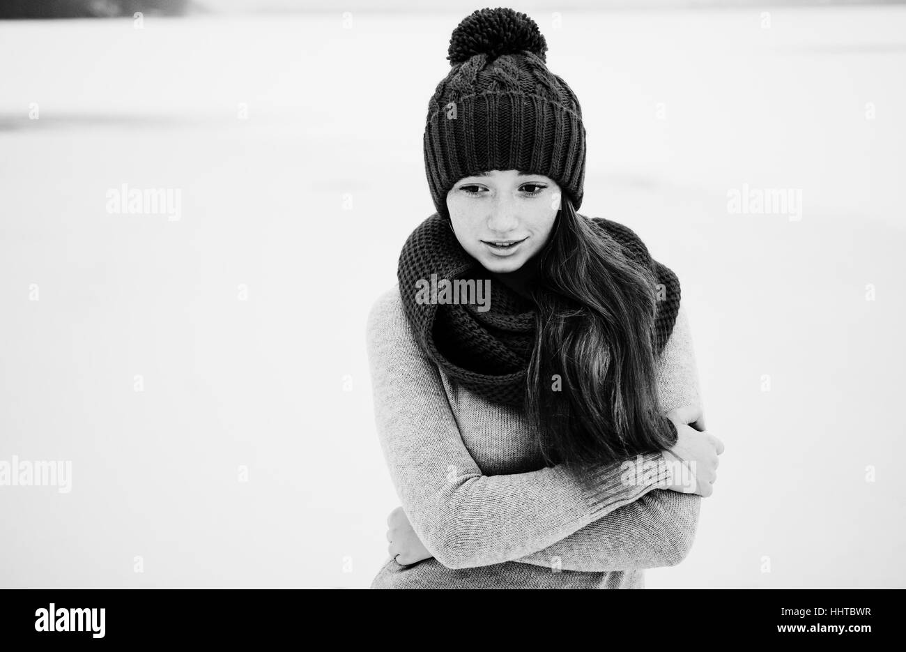 Ritratto di giovane Capelli rossi ragazza con lentiggini usura a maglia blu cappello di lana e sciarpa in giornata invernale di ghiaccio in background. Foto in bianco e nero Foto Stock