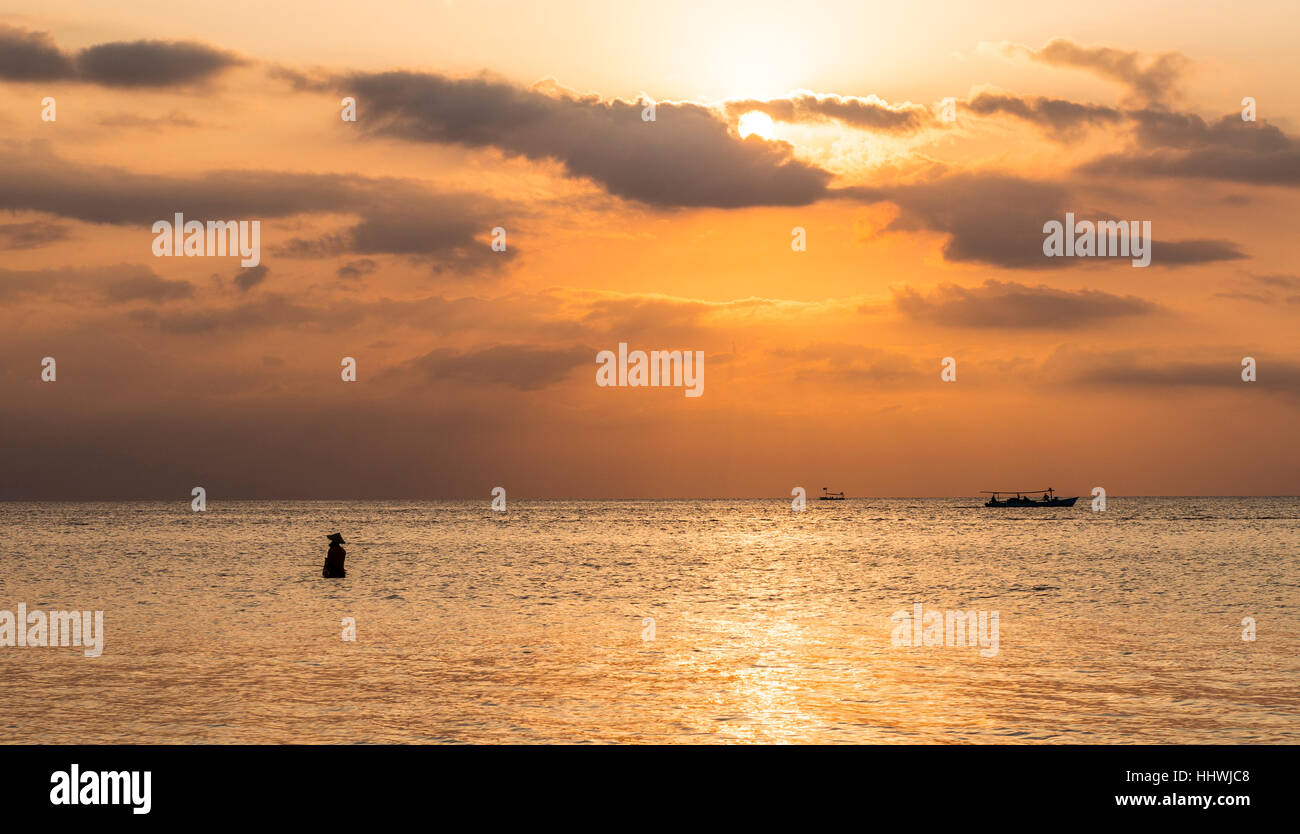 Tramonto sul mare, pescatore in piedi in acqua, retroilluminato, Lovina Beach, Bali, Indonesia Foto Stock