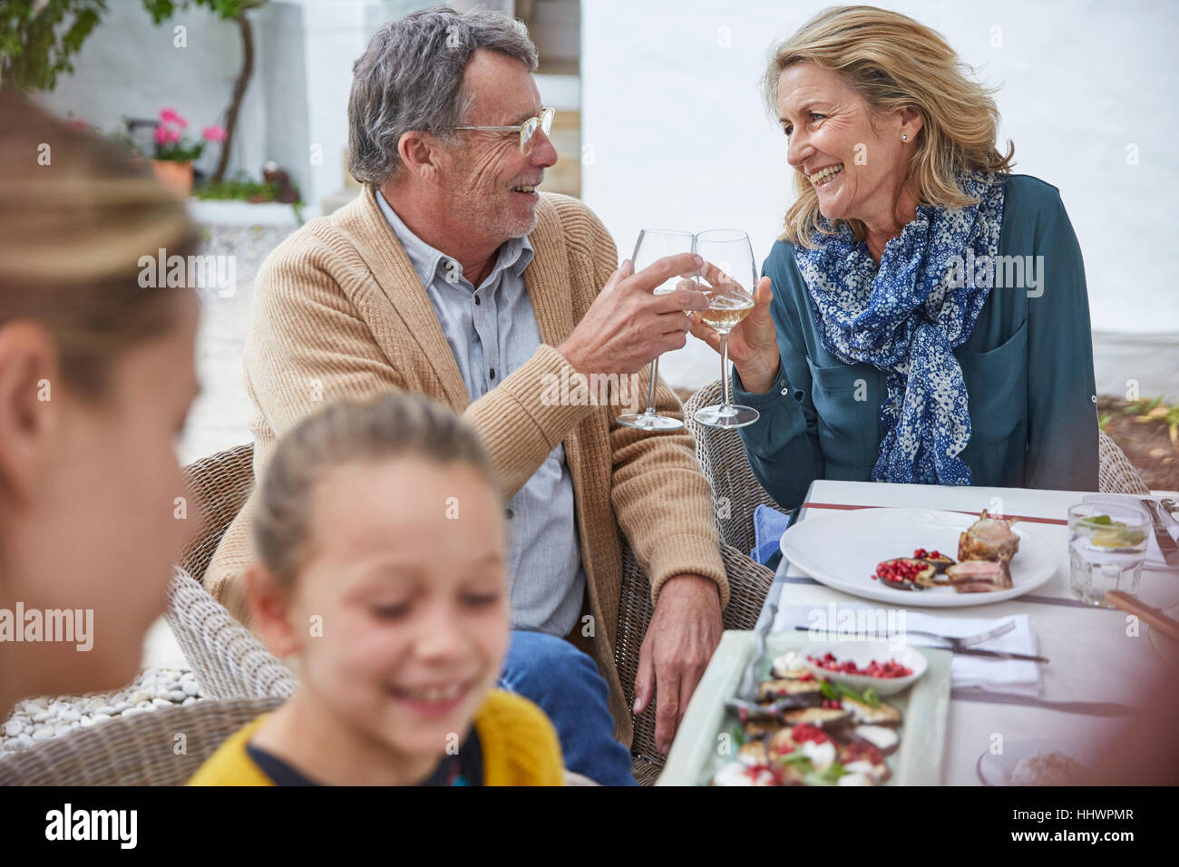 Felice coppia senior tostare calici da bianco al patio pranzo Foto Stock