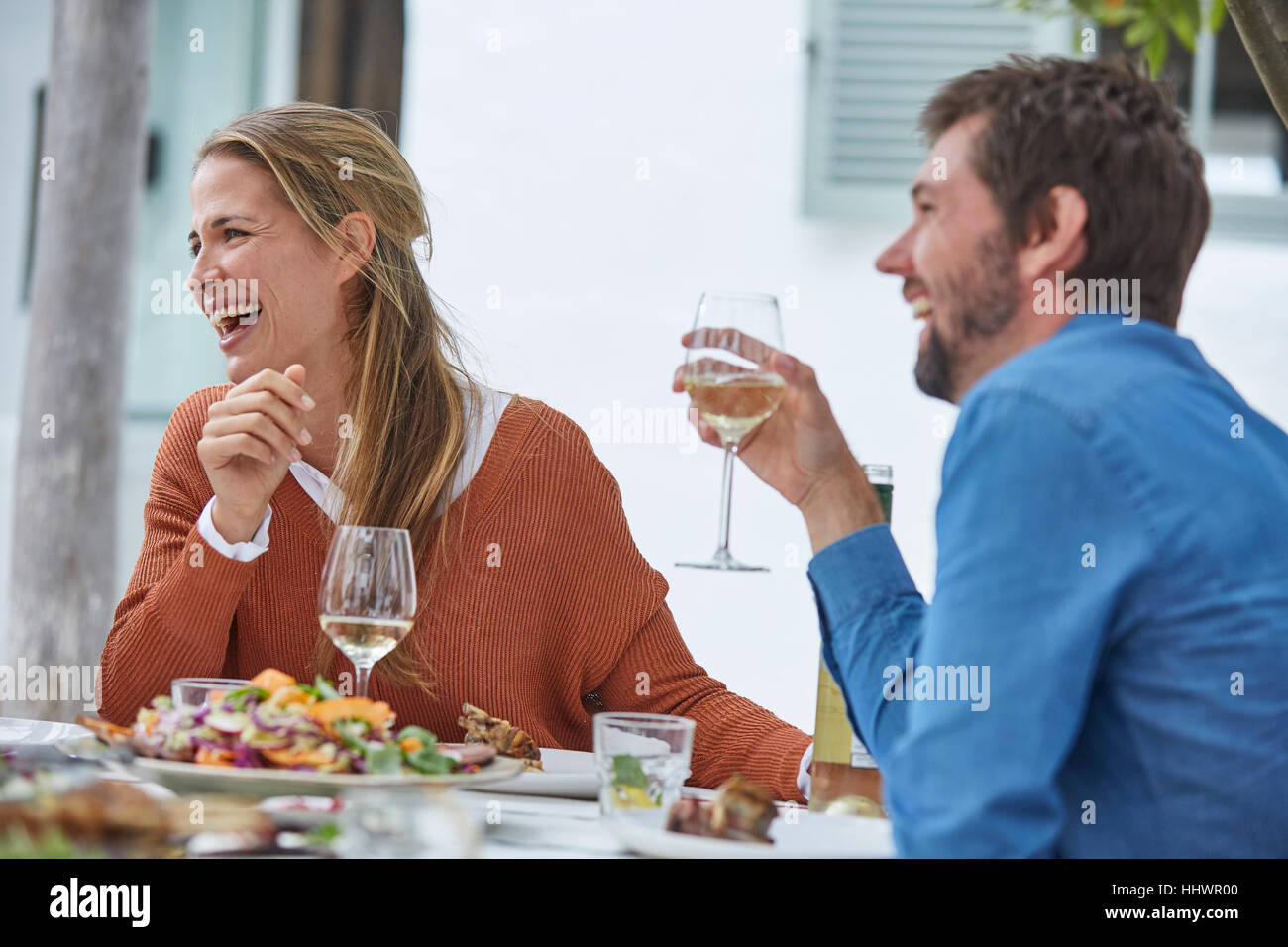 Ridere paio di bere il vino bianco e mangiare il pranzo al patio tabella Foto Stock