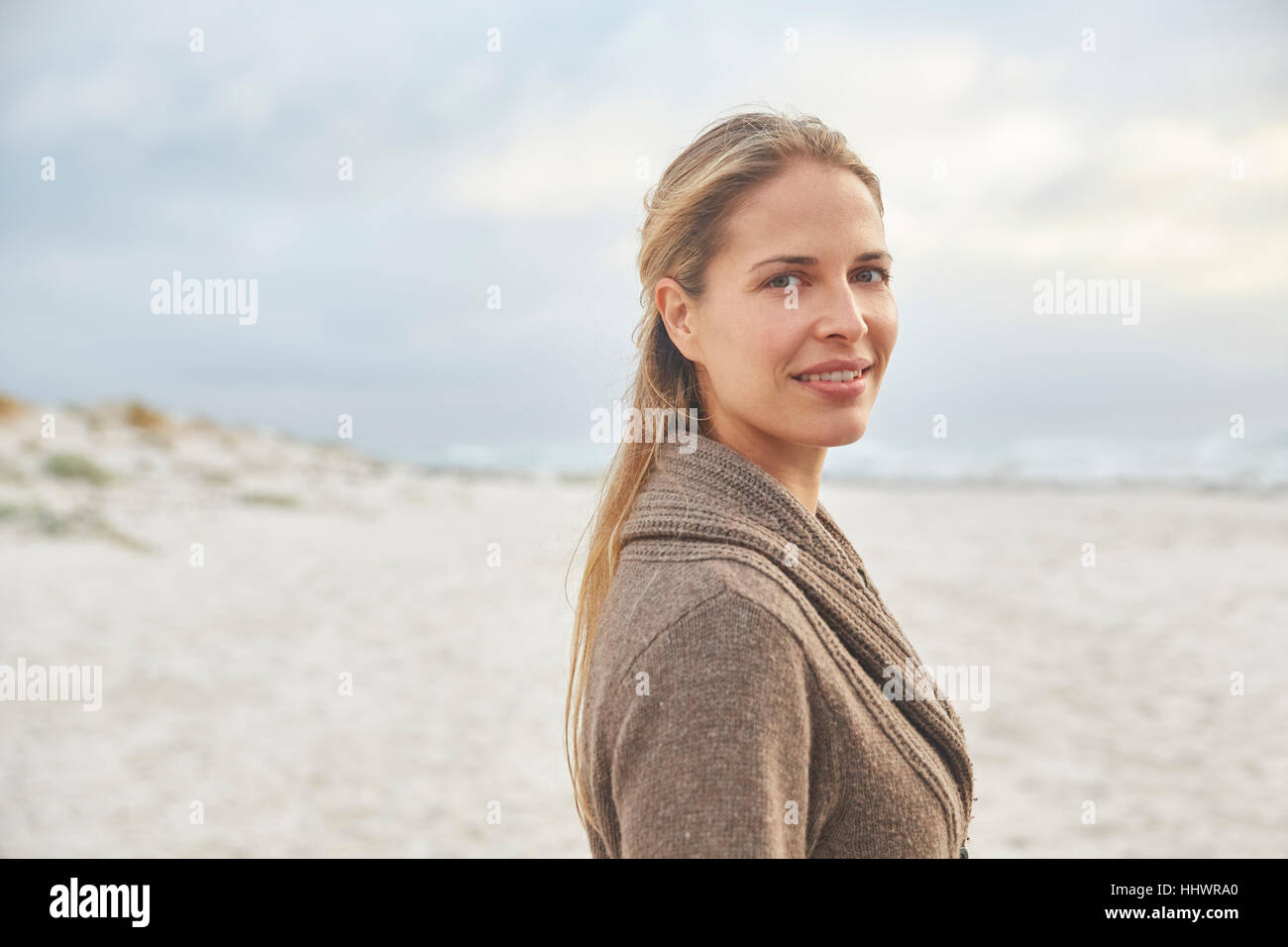 Ritratto sorridente donna bionda sulla spiaggia invernale Foto Stock