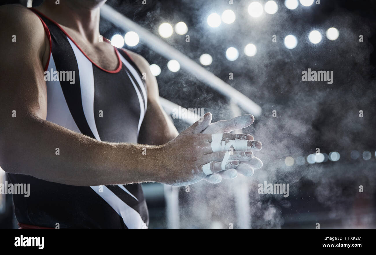 Maschio di sfregamento ginnasta chalk polvere sulle mani sotto le barre parallele Foto Stock