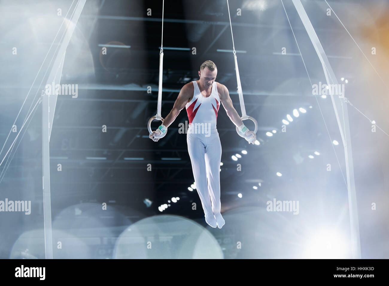 Focalizzato ginnasta maschio di eseguire su anelli di ginnastica in arena Foto Stock
