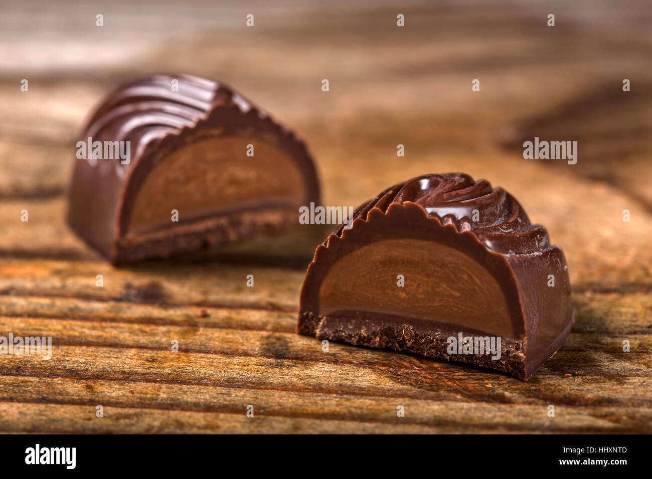 Un cioccolato fondente candy tagliato a metà su sfondo di legno Foto Stock