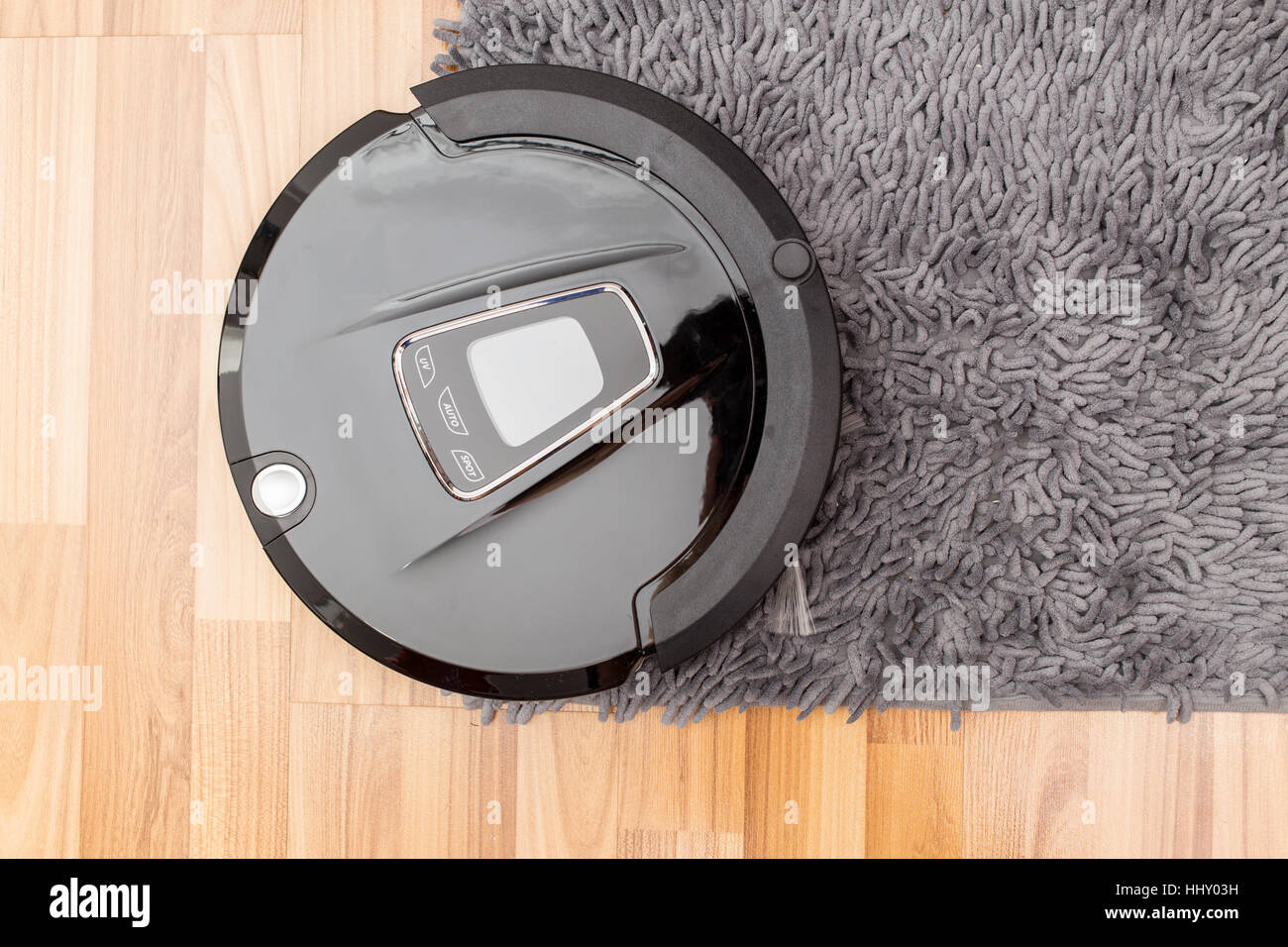 Robotica aspirapolvere su legno parquet, Smart vuoto, nuova tecnologia di automatizzare i lavori di casa - Pulizia sul tappeto. Foto Stock