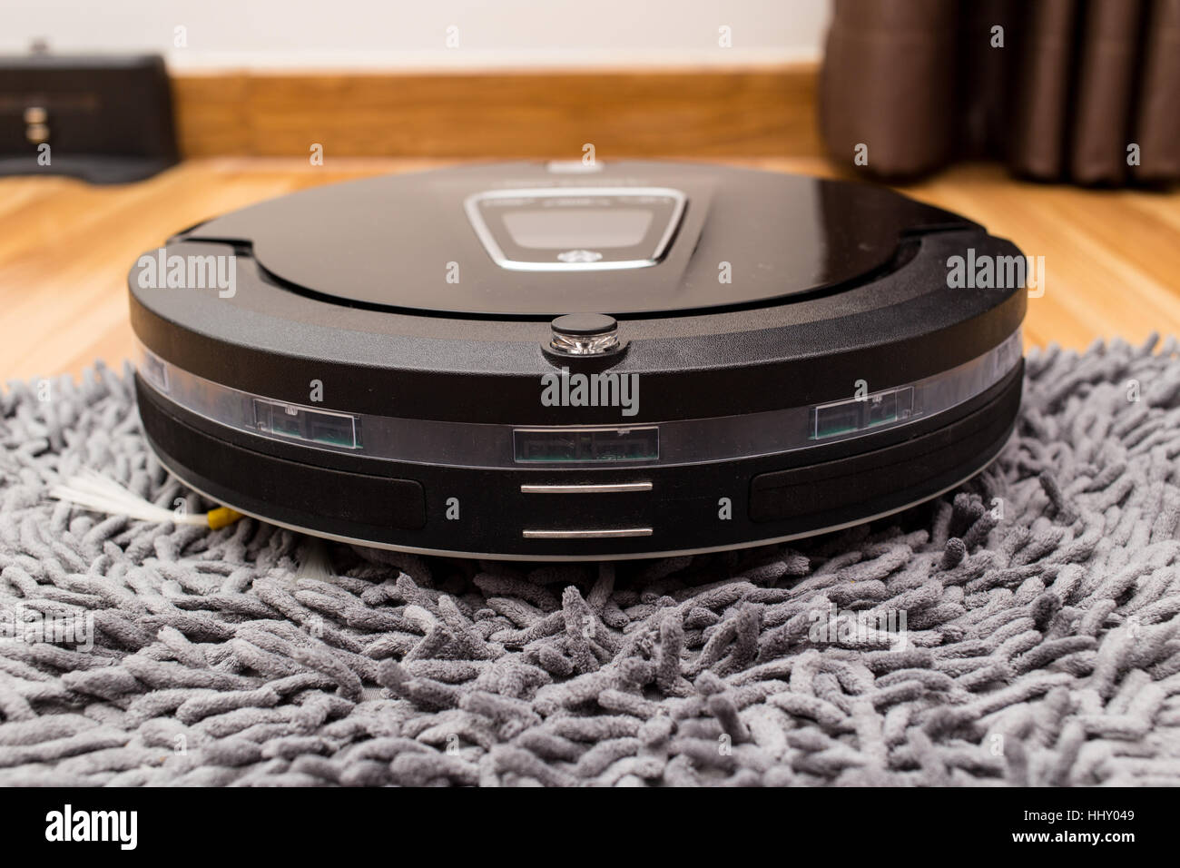 Robotica aspirapolvere su legno parquet, Smart vuoto, nuova tecnologia di automatizzare i lavori di casa - Pulizia sul tappeto. Foto Stock