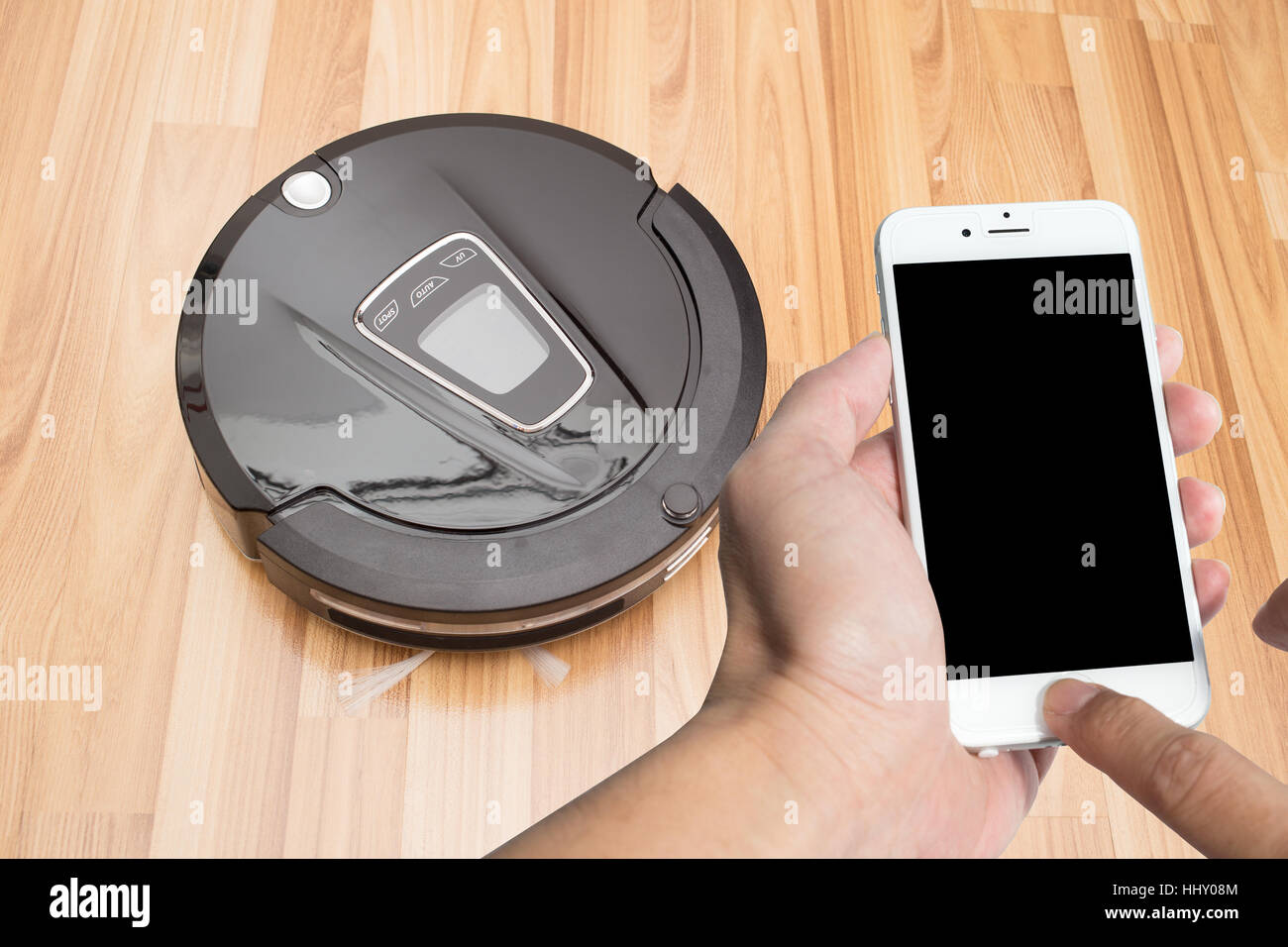 Smart phone touch screen robotici con aspirapolvere su legno parquet, Smart vuoto, nuova tecnologia di automatizzare i lavori di casa. Foto Stock