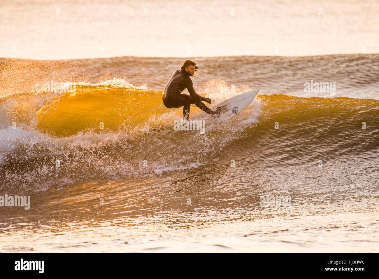 Aberystwyth Wales UK, sabato 21 gennaio 2017 UK meteo: dopo un freddo la notte, con temperature ben al di sotto dello zero, surfisti godersi le onde al tramonto alla fine di una bella giornata di sole caldo in Aberystwyth su Cardigan Bay costa del Galles occidentale foto Keith Morris / Alamy Live News Foto Stock