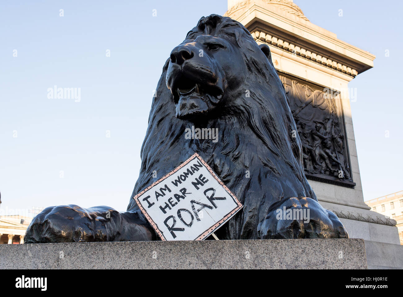 London, Regno Unito - 21 gennaio 2017. Lion statua in segno di protesta al di sotto. Migliaia di manifestanti radunati in Trafalgar Square a frequentare le donne del marzo contro Donald Trump chiamando per i diritti umani e la parità. Foto Stock