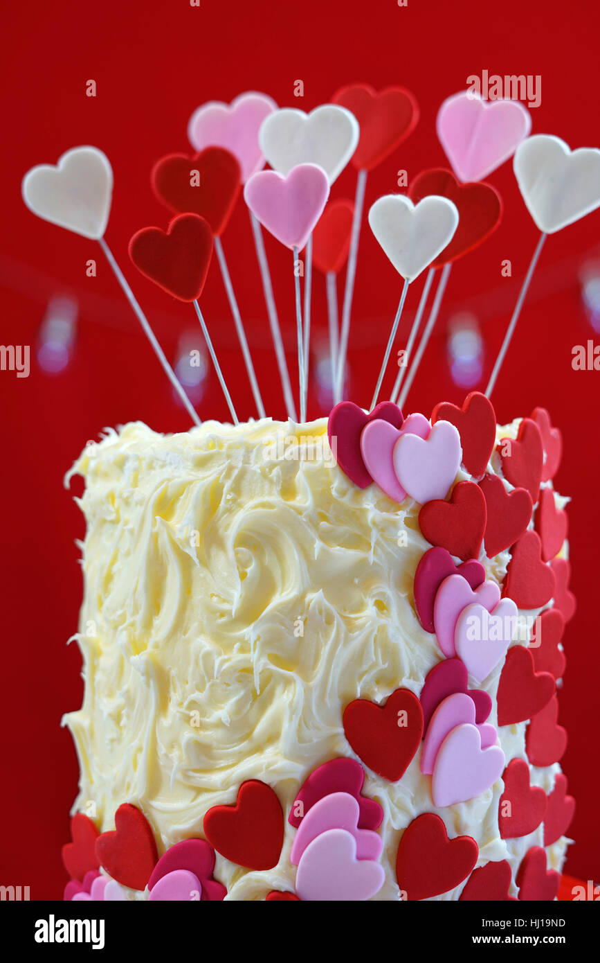 Il bel St Valentines Day parte tabella con impediva di procedere rosso, bianco e cuori rosa double layer cake, bianco con glassa di cioccolato. Foto Stock