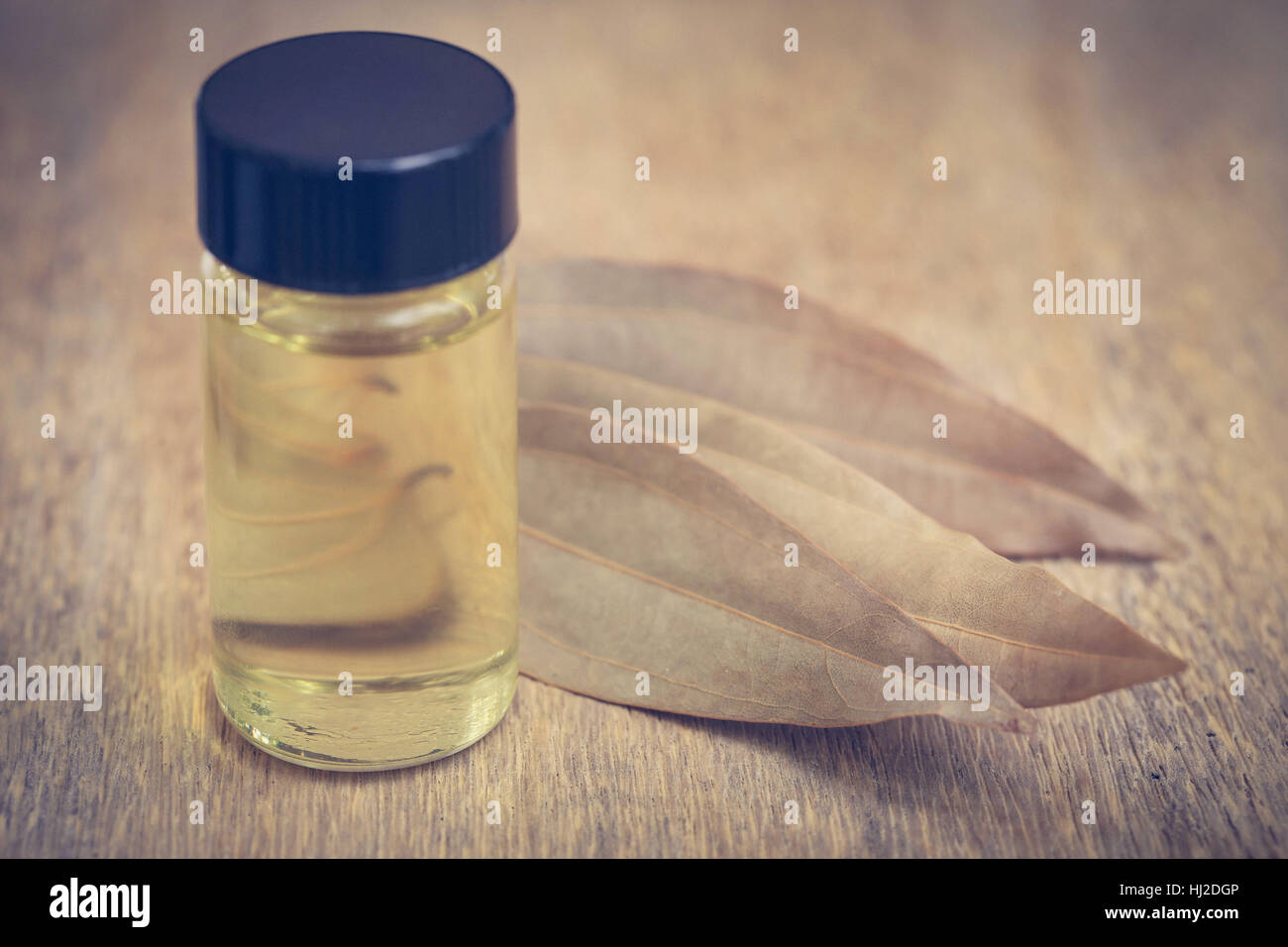 Foglie di alloro con olio essenziale in bottiglia su una superficie di legno Foto Stock