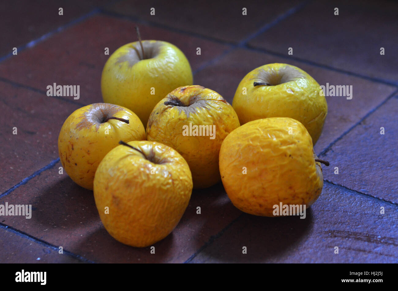 Vecchie mele marcio su piastrelle Foto Stock