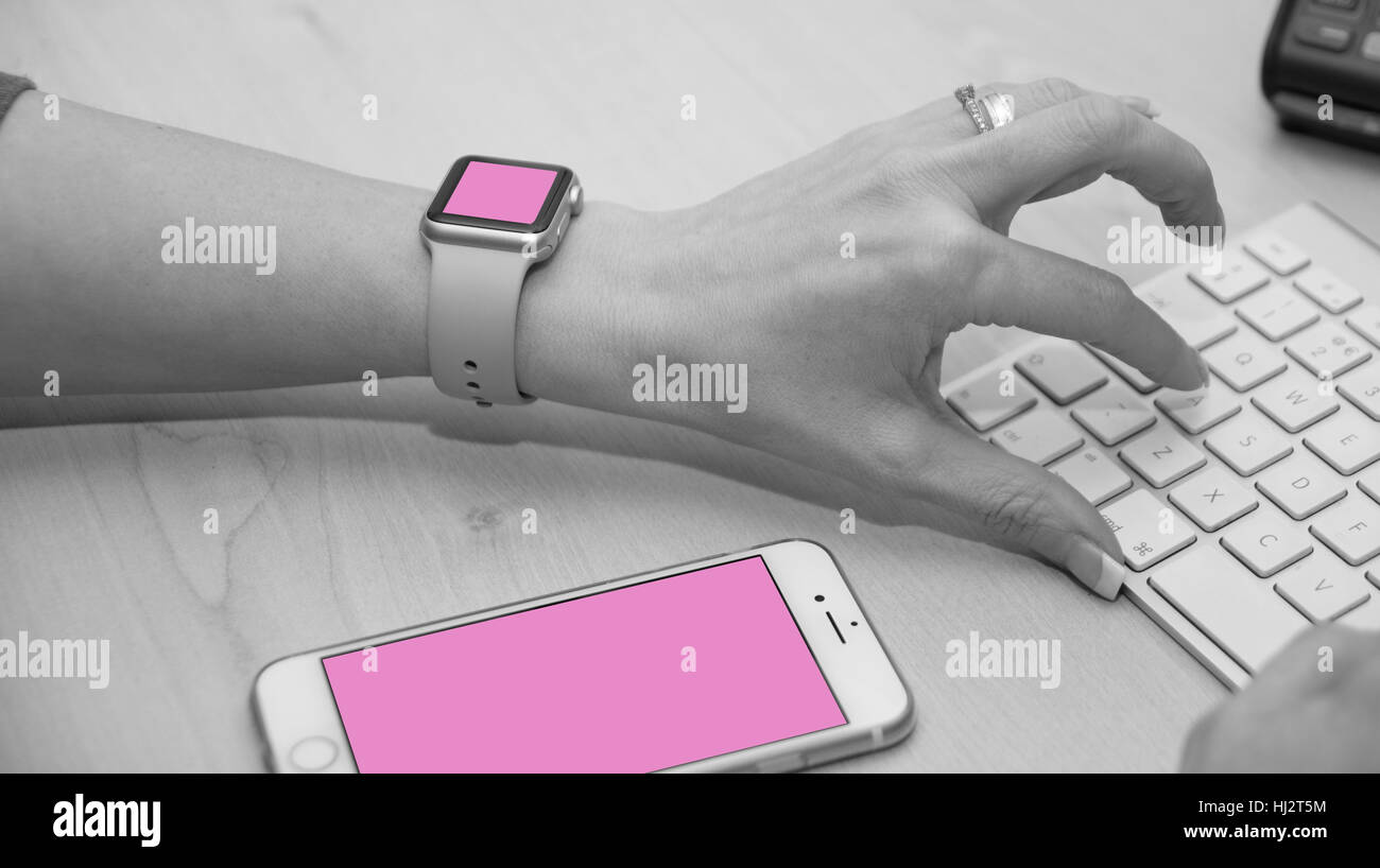 Il personale di assistenza la digitazione sulla tastiera. Shot mostra anche iWatch e iPhone. Foto Stock