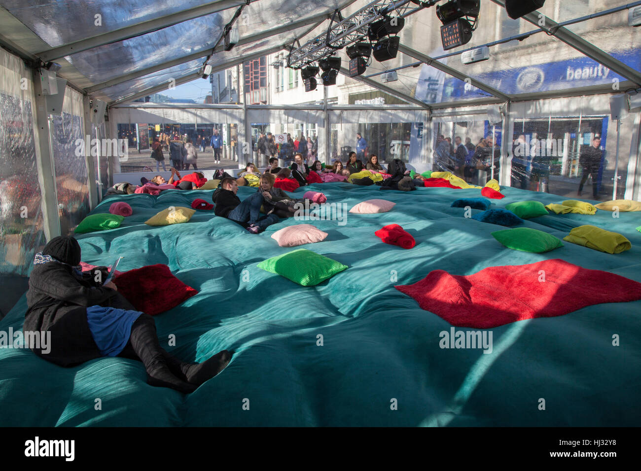 Persone coperte di coperte, campeggiare con il freddo e guardare un film nella tenda di riscaldamento di Vilaint, Piccadilly, Manchester, Regno Unito Foto Stock