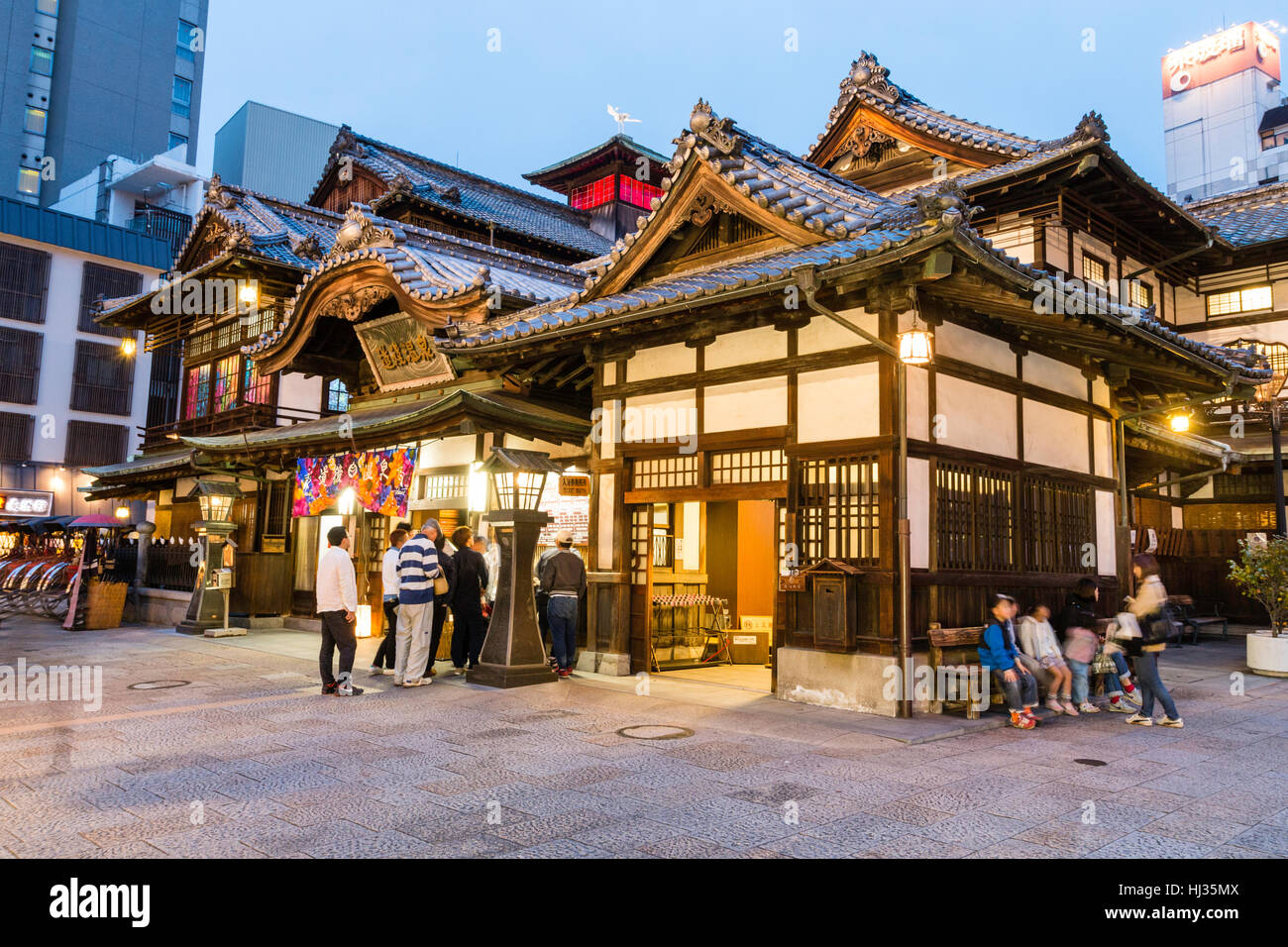 Giappone, Matsuyama. Famosa attrazione turistica, il Dogo Onsen edificio. Ingresso anteriore con le persone che si recano in, di notte. Foto Stock