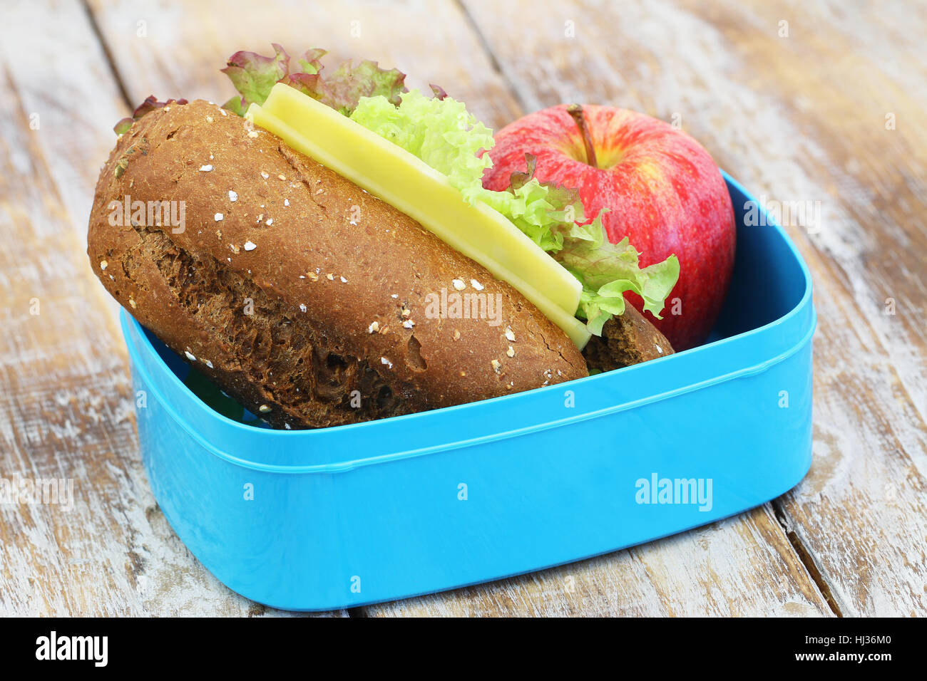 Pranzo al sacco contenente marrone sandwich di pane con formaggio e lattuga e mela rossa Foto Stock