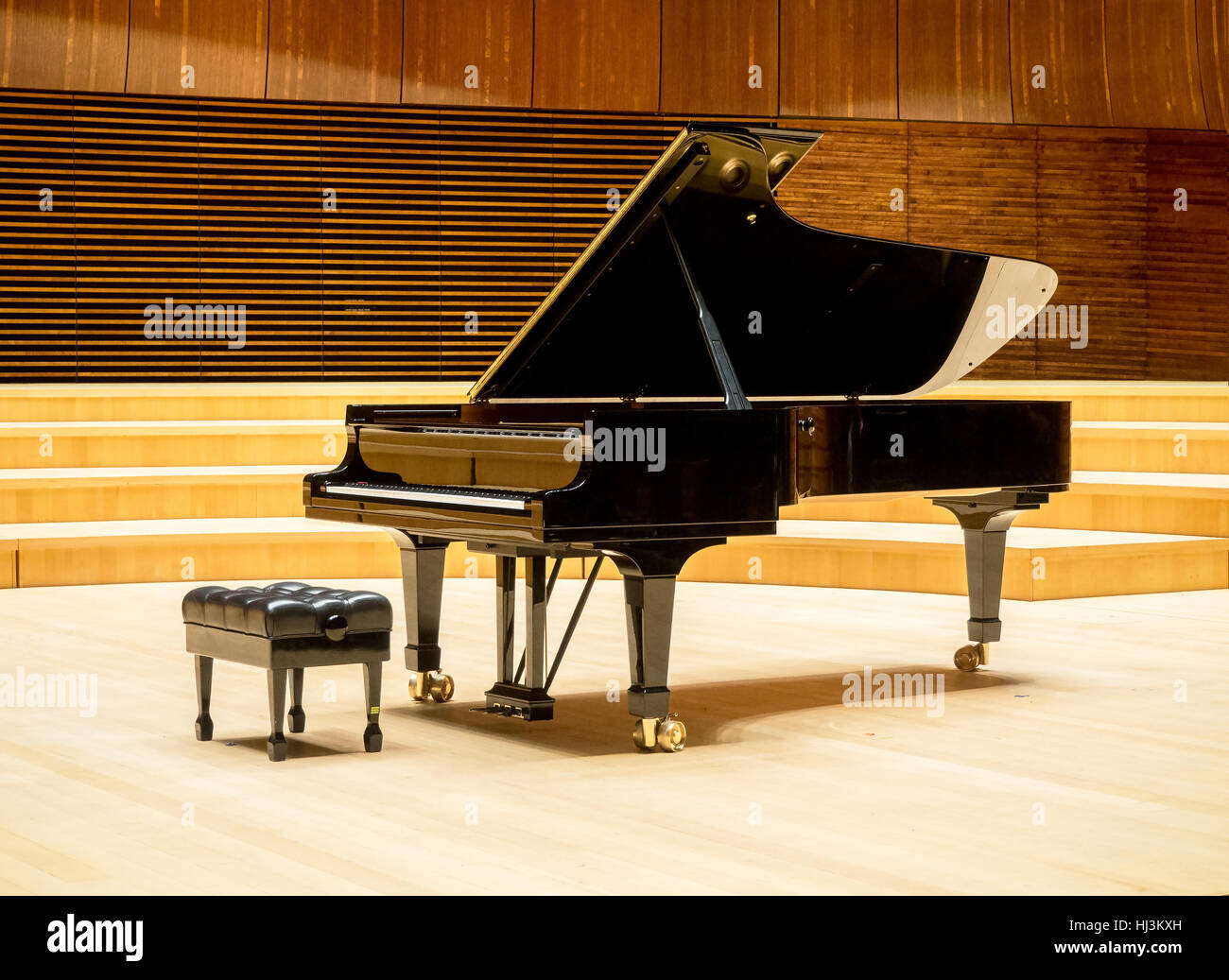 Un grande pianoforte su un palco di legno di una sala da concerto Foto Stock
