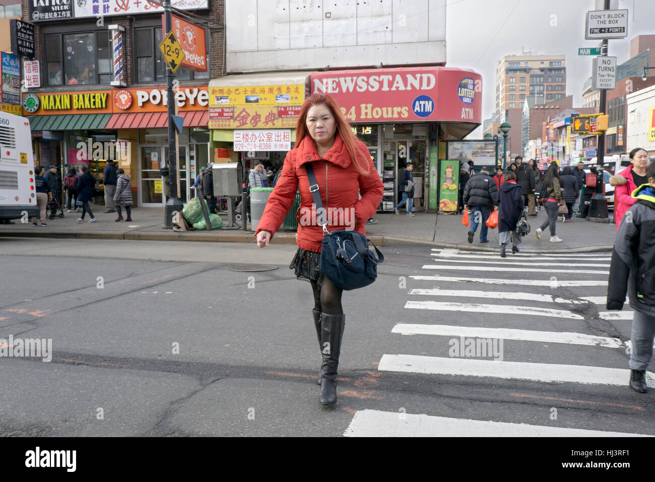 Un americano asiatico donna in un CORTO MANTELLO e luminose rivestire attraversando Roosevelt Ave. in Chinatown, lavaggio, Queens, a New York City Foto Stock