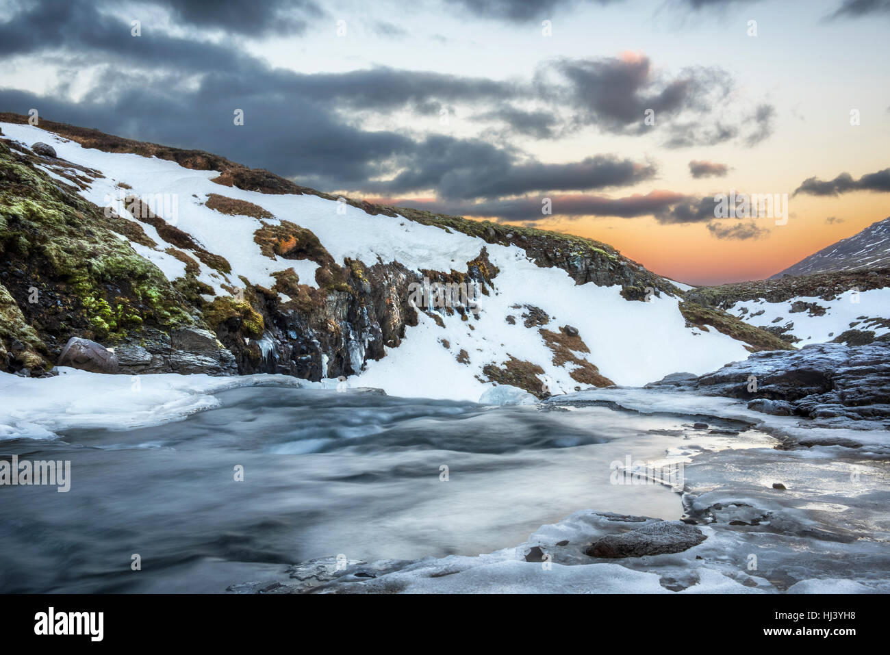 Un freddo fiume nevoso nelle Highlands di Islanda incorniciata dai cieli pastello e scoscesi offre paesaggio panoramico epitomizing congelata di deserto. Foto Stock