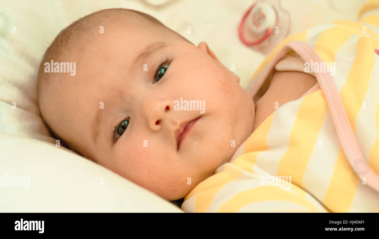 Piccolo bambino sdraiato sul letto di close-up verticale Foto Stock