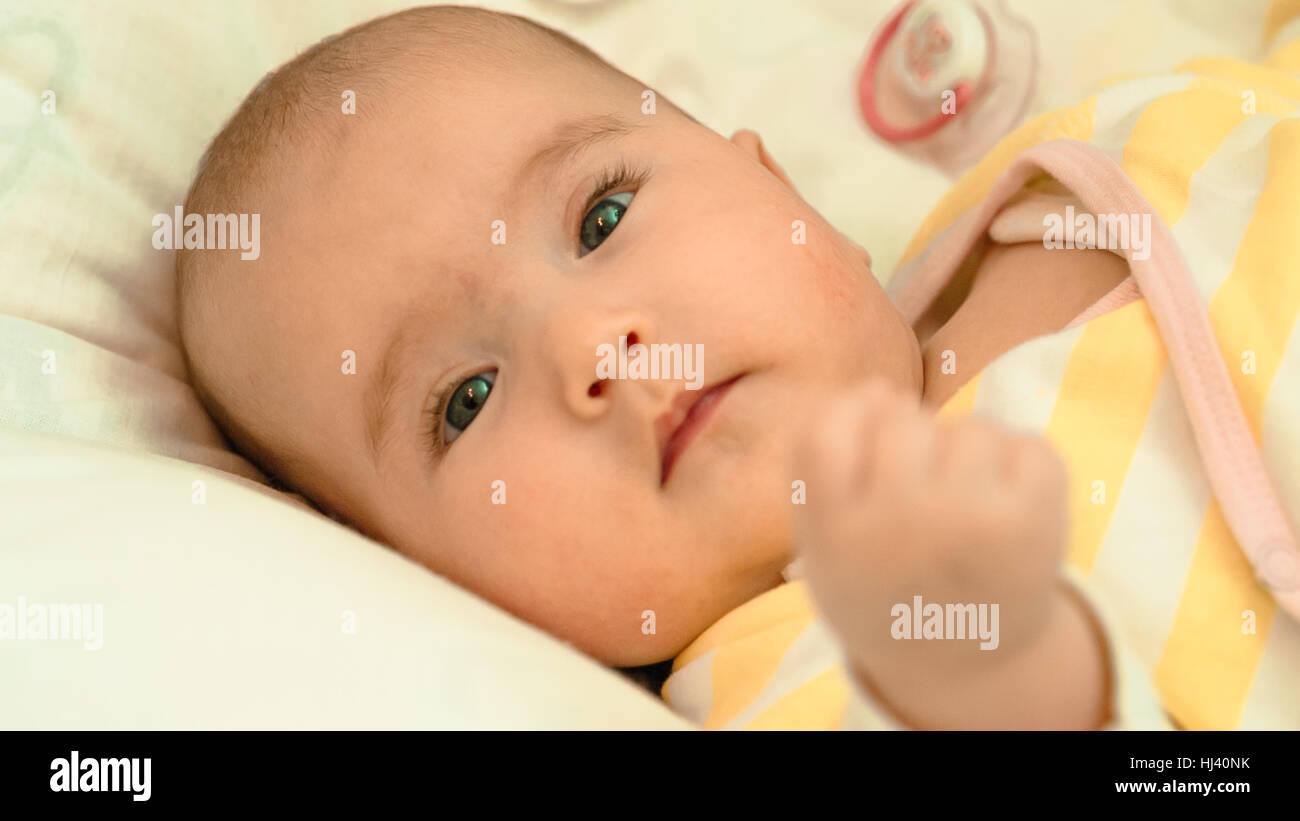 Piccolo bambino sdraiato sul letto di close-up verticale Foto Stock