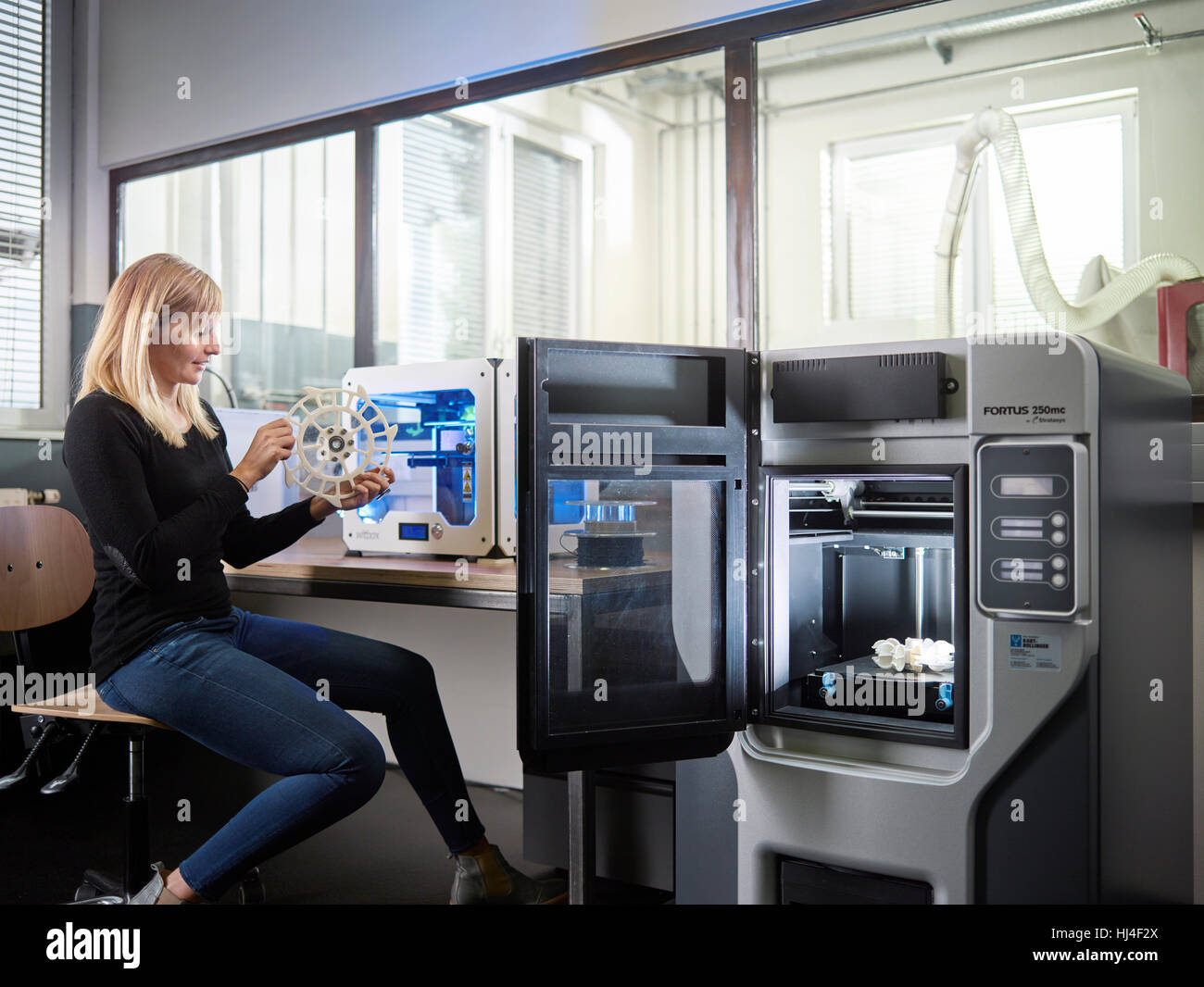 Dipendente, 25-30 anni, la parte di controllo di stampante 3D nel laboratorio di produzione, FabLab, Wattens, Tirolo, Austria Foto Stock