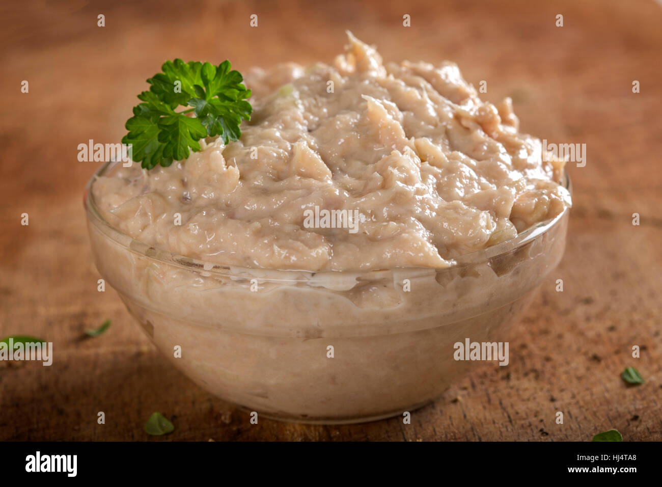 Ciotola riempita con crema fatta dal tonno, il burro e la cipolla su sfondo di legno Foto Stock