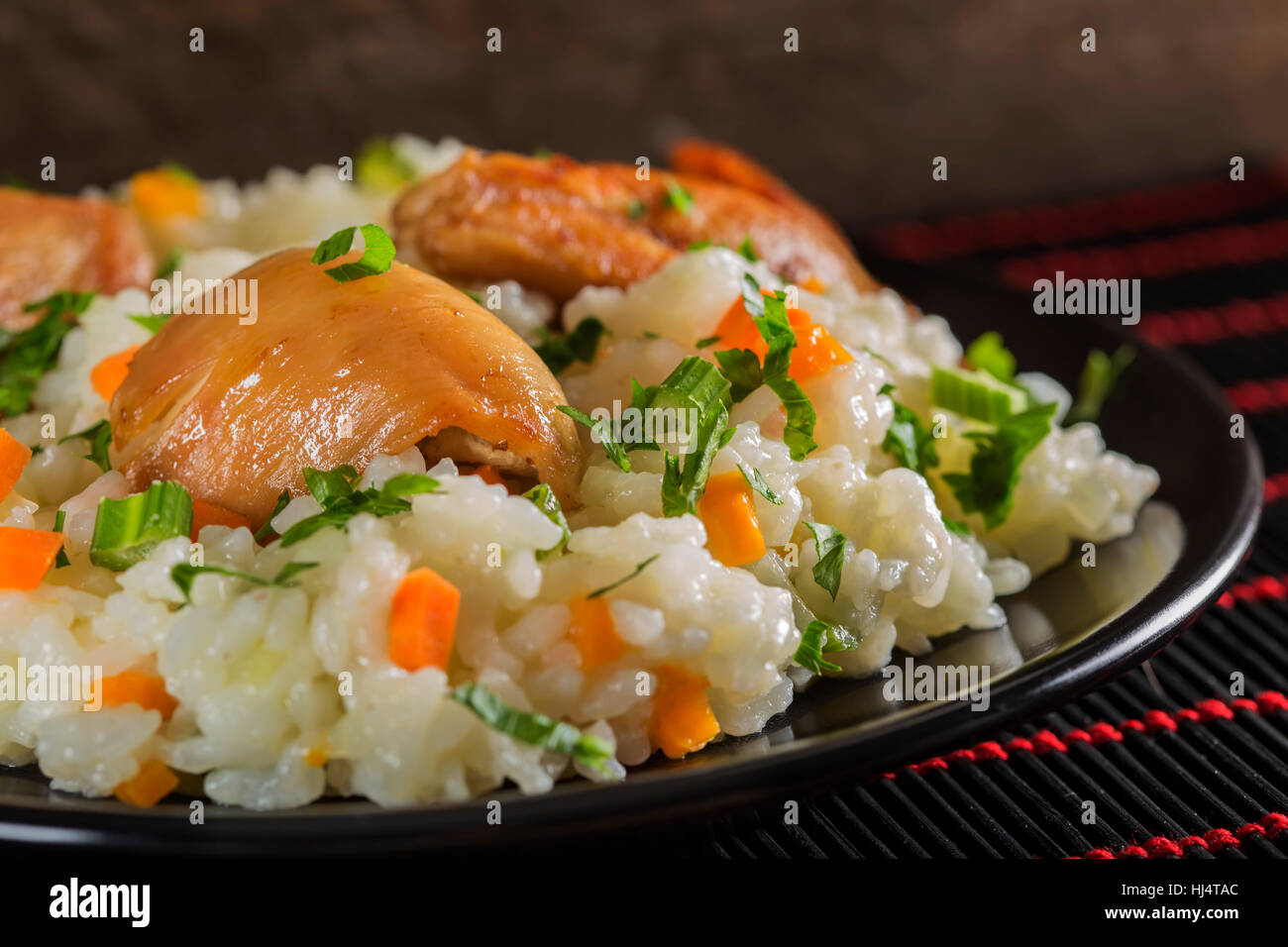 Pilaf - rumeno tradizionale cibo fatto con carne di pollo, riso e verdure su sfondo scuro Foto Stock
