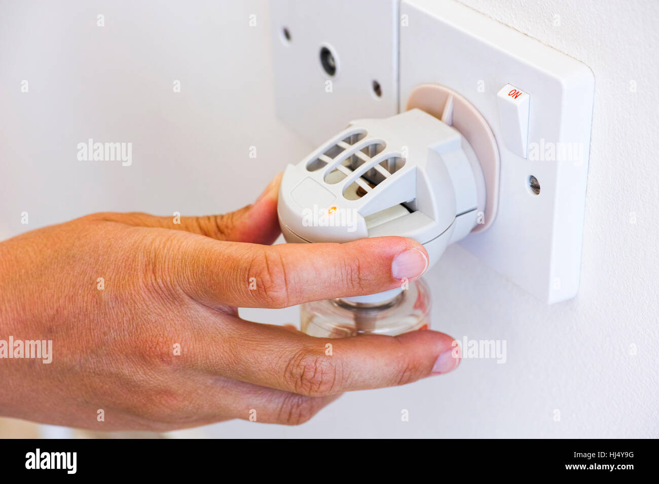 Donna girando a mano su anti-zanzara fumigator nella presa di corrente . Foto Stock