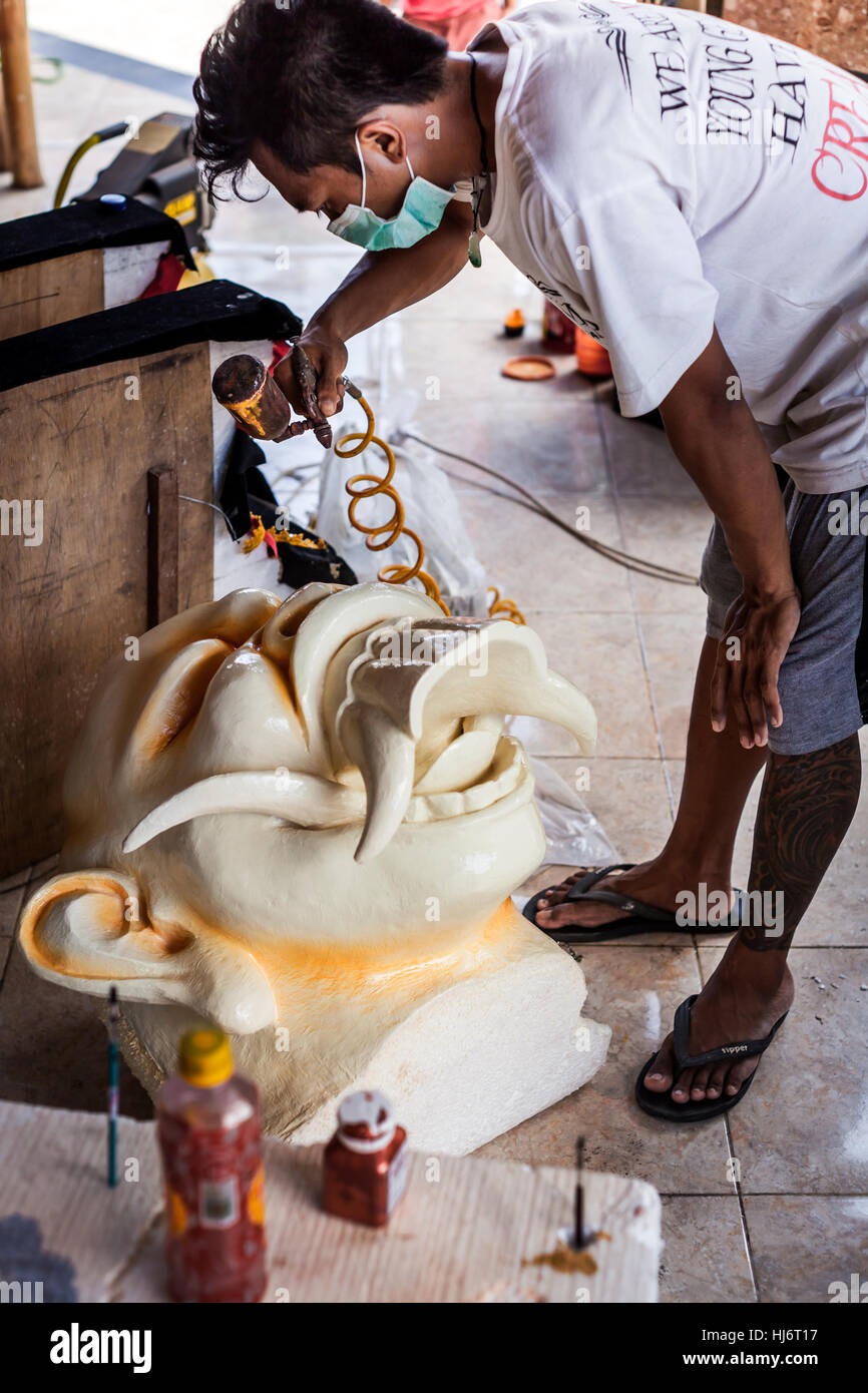 Ragazzo indonesiano verniciatura a spruzzo di un enorme demone Ogoh-Ogoh-testa simile a Bali per la festa religiosa sfilata di Ngrupuk Balinese su Capodanno Foto Stock