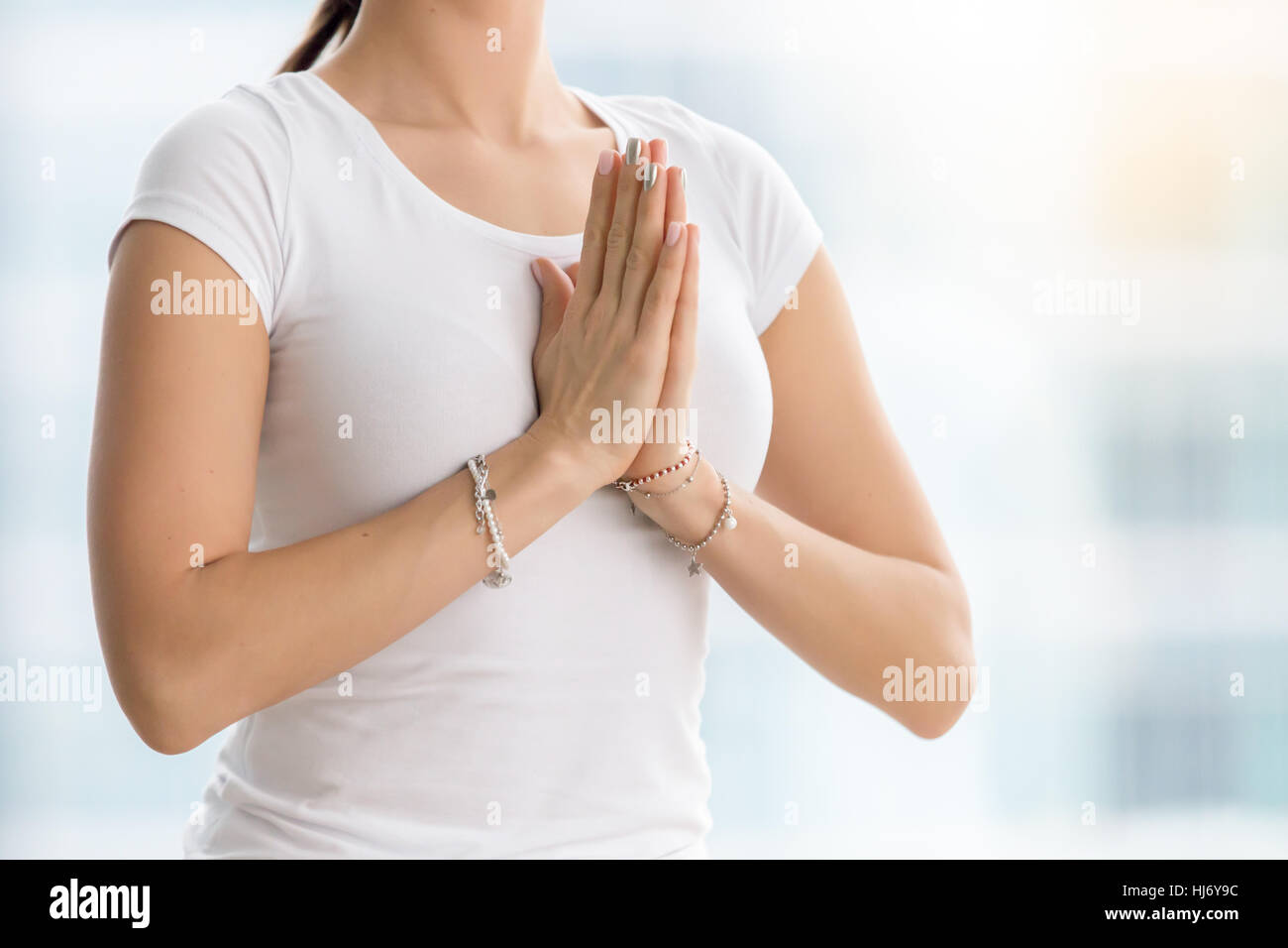La donna in bianco t-shirt rendendo namaste gesto, primo piano Foto Stock
