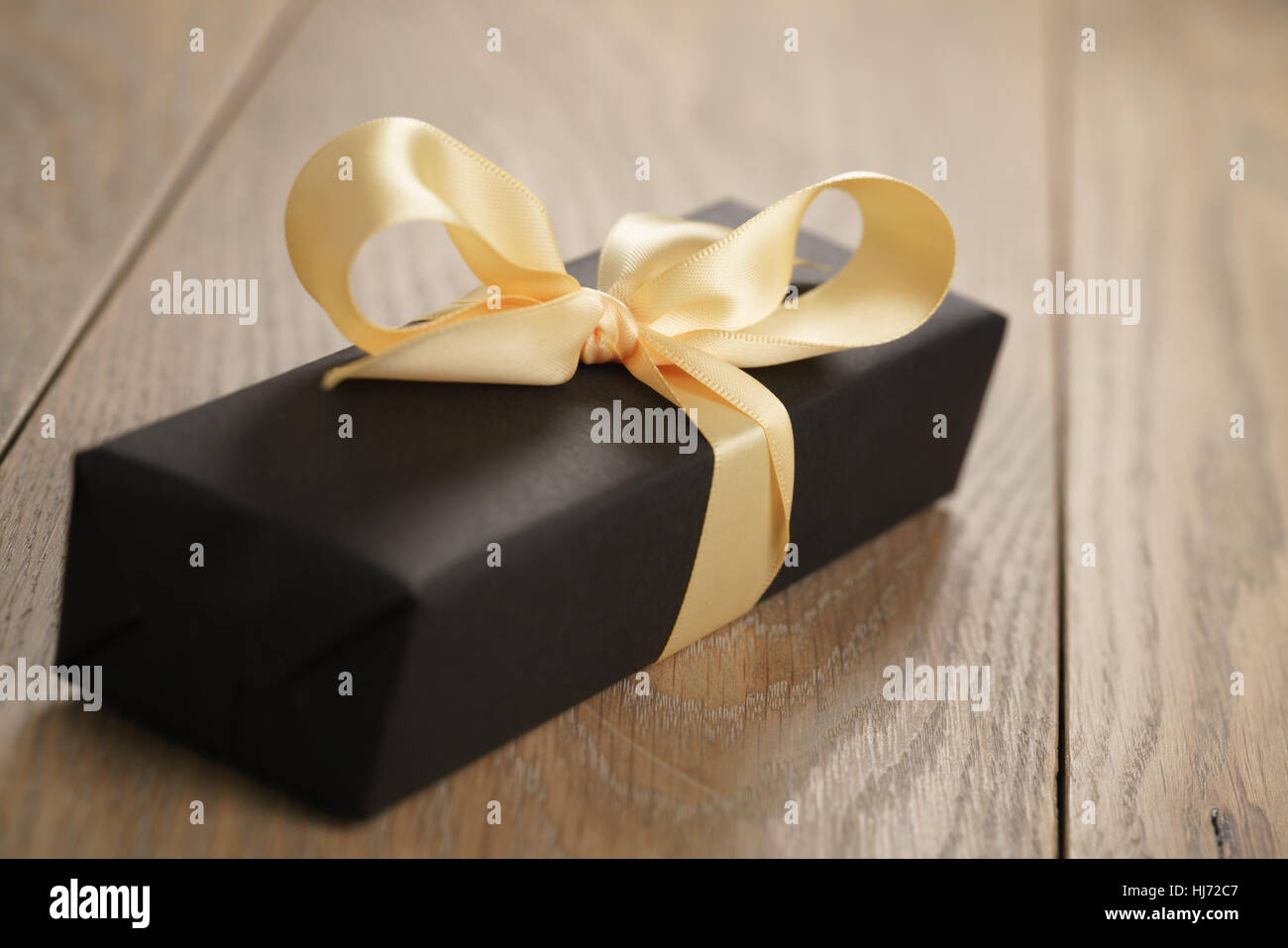 Dono fatti a mano carta nera scatola con nastro giallo arco sul tavolo di legno Foto Stock