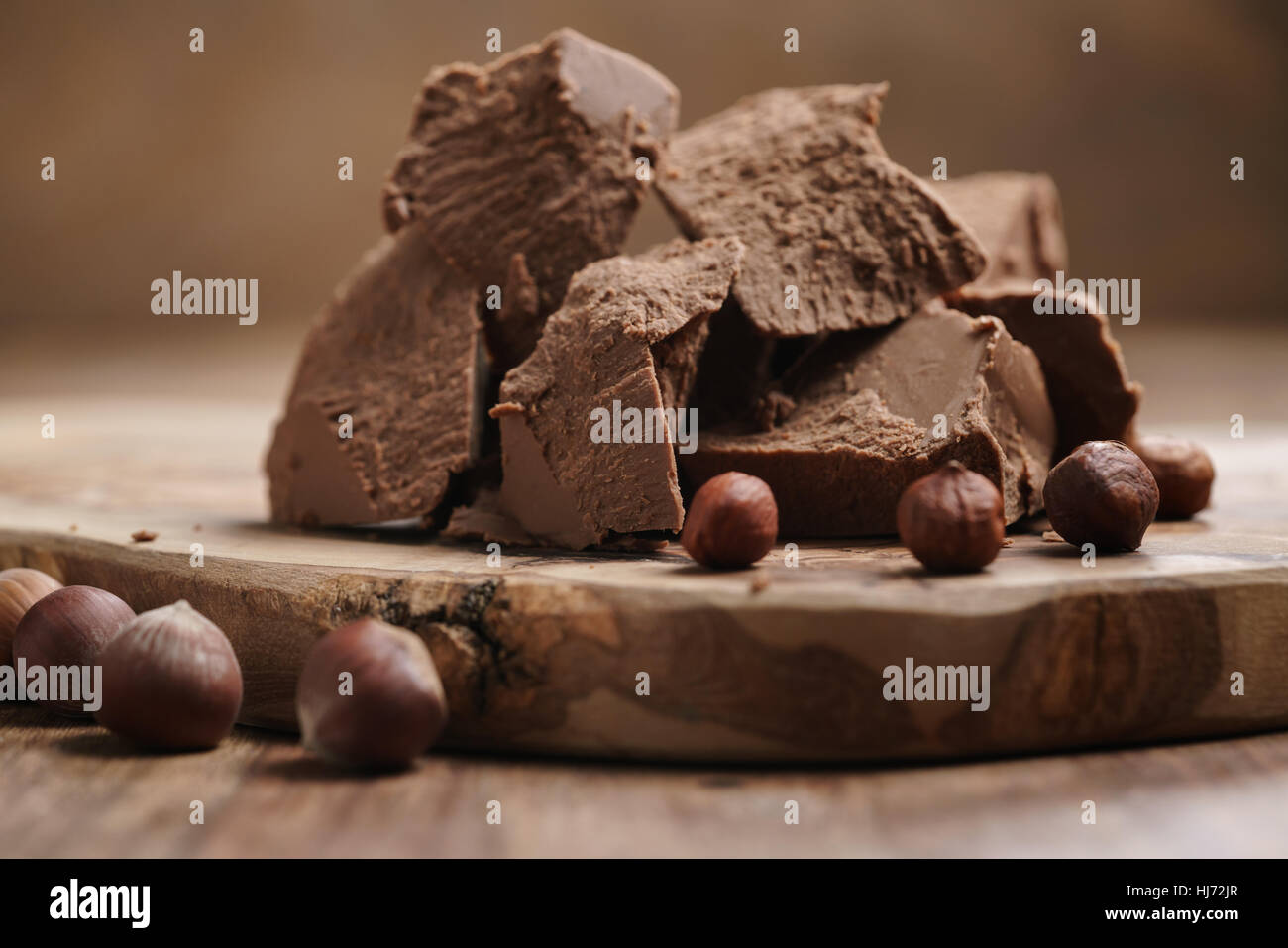 Blocchi di gianduja con nocciole sul pannello di legno Foto Stock