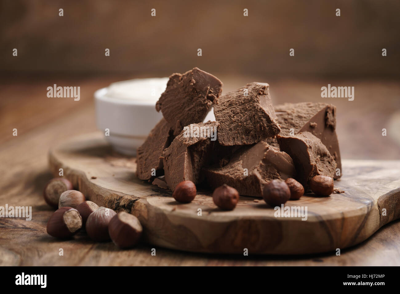 Blocchi di gianduja con nocciole e crema su pannello di legno Foto Stock