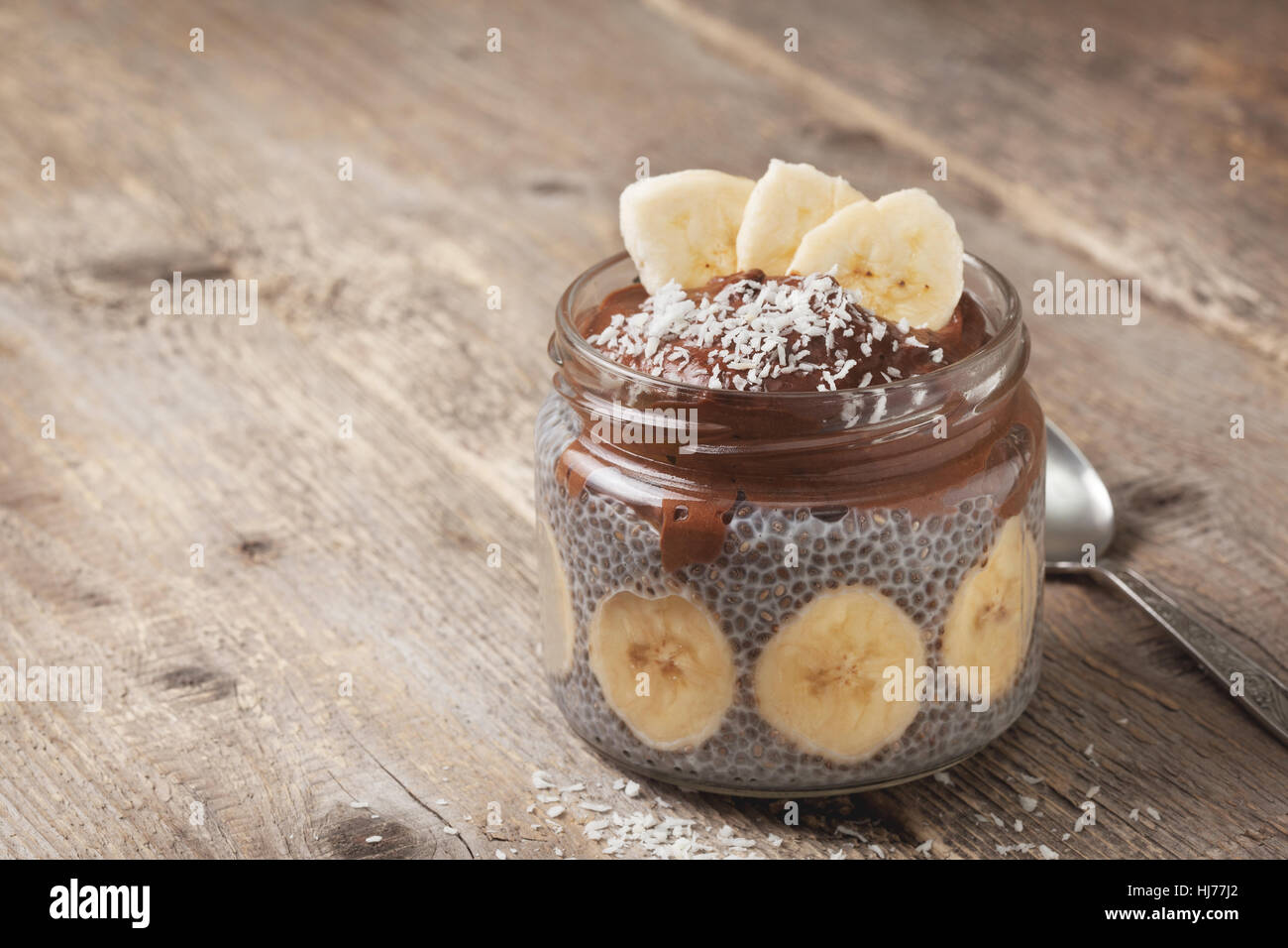 Budino di chia con cioccolato frullato di banane in un vasetto di vetro sul vecchio sfondo di legno Foto Stock