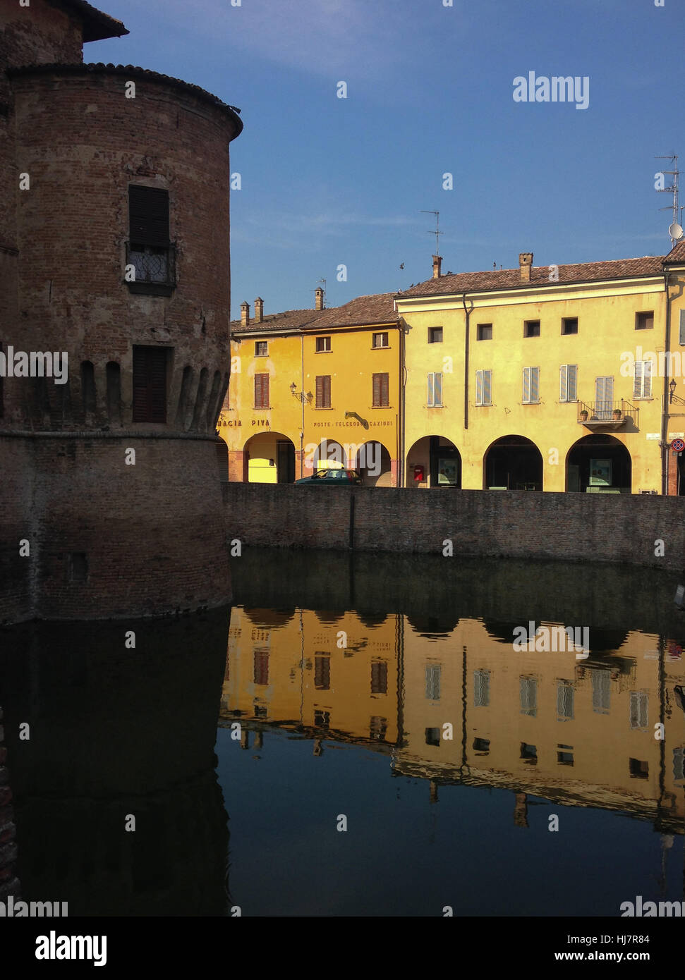 Il castello di Fontanellato e degli edifici circostanti si riflette nell'acqua durante il tramonto. L'Italia. Foto Stock