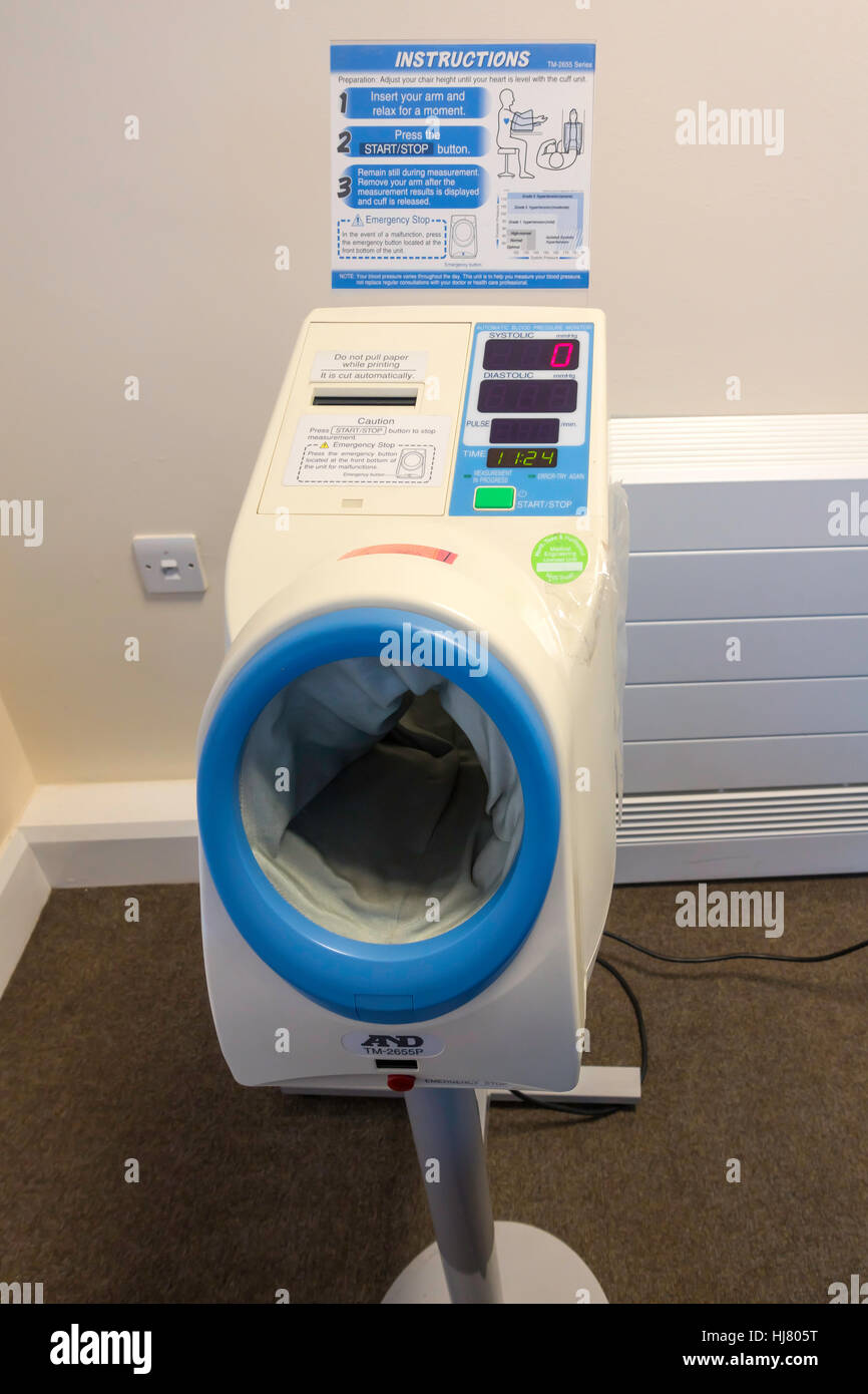 Self service di pressione del sangue prova la macchina in un NHS medico di medicina generale chirurgia della sala di attesa Foto Stock