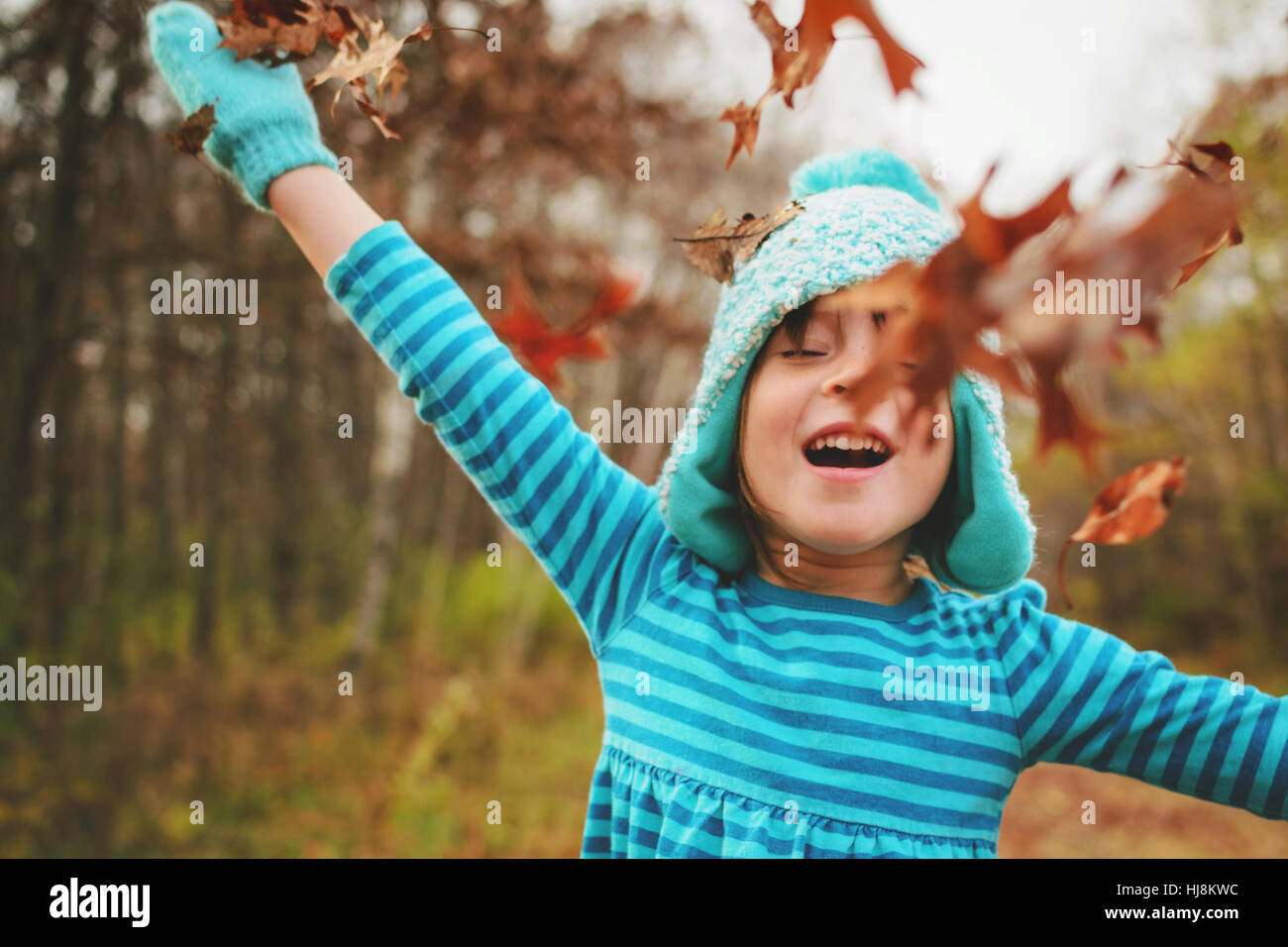 Ragazza gettando le foglie di autunno in aria Foto Stock