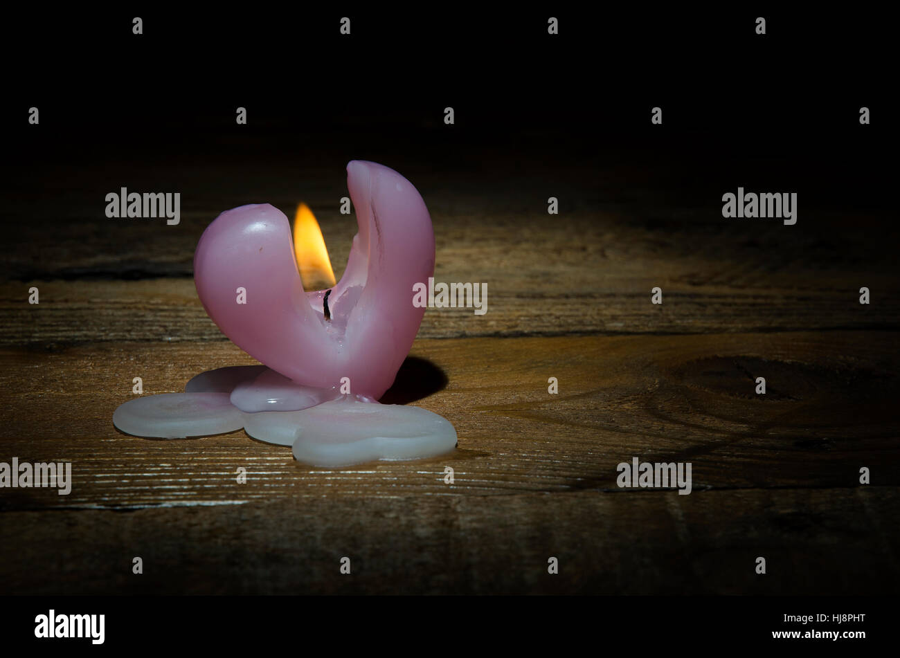 Candela che brucia in forma di cuore su uno sfondo scuro per il giorno di San Valentino. Foto Stock