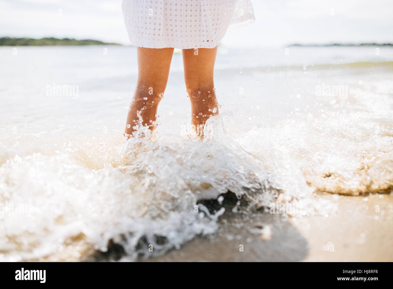 Ragazza in piedi sulla spiaggia con spruzzi delle onde le sue gambe, teste di Noosa, Queensland, Australia Foto Stock Ragazza in piedi sulla spiaggia con spruzzi delle onde le sue gambe, teste di Noosa, Queensland, Australia Foto Stock
