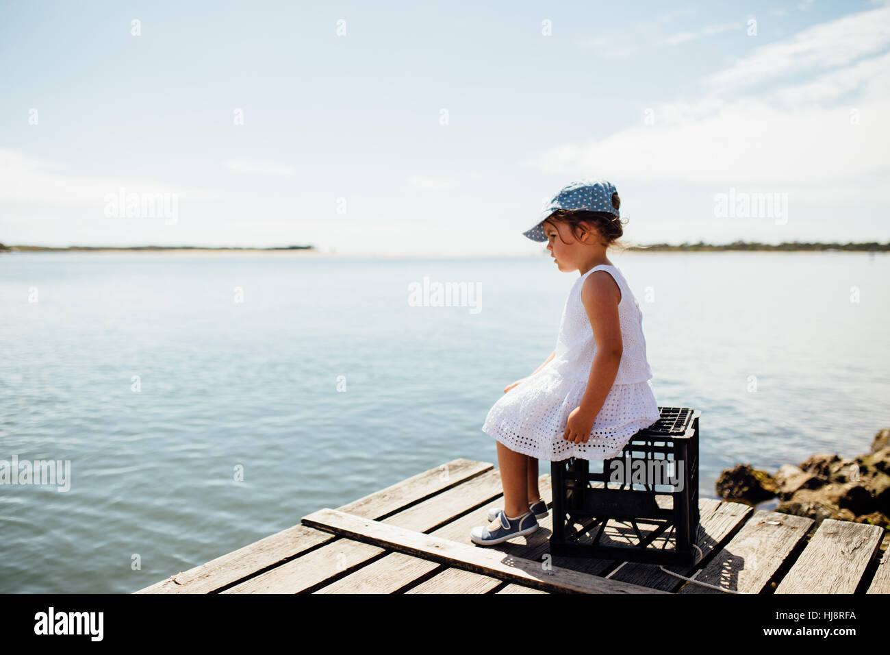 Ragazza seduta su di una cassa in un dock, teste di Noosa, Queensland, Australia Foto Stock Ragazza seduta su di una cassa in un dock, teste di Noosa, Queensland, Australia Foto Stock