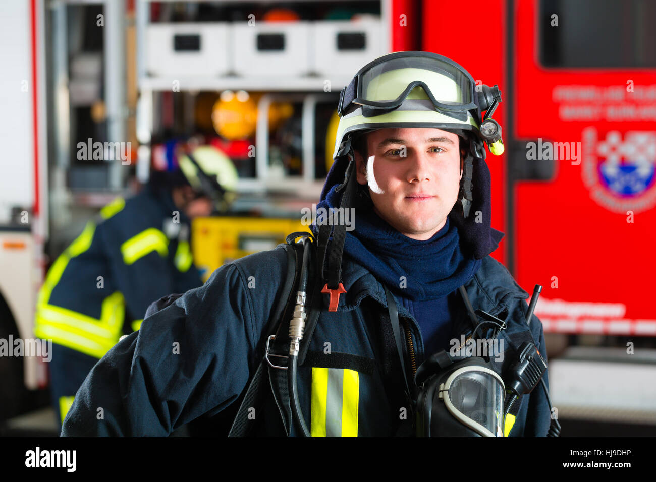 Vigile del fuoco in piedi in uniforme nella parte anteriore di un incendio Foto Stock