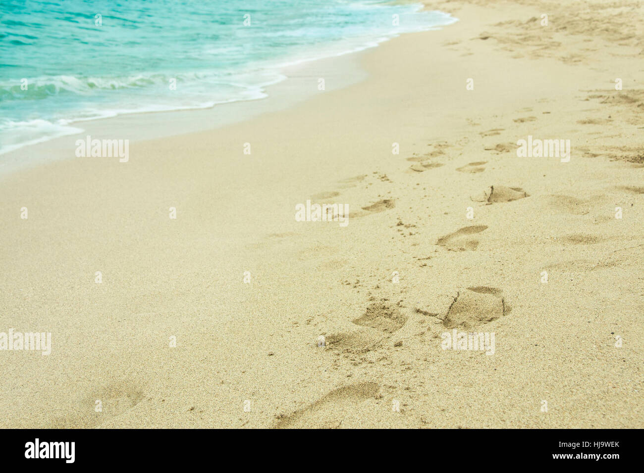 Sandy impronte sulla isola spiaggia tropicale nel bel mezzo della giornata soleggiata vicino oceano turchese wave estate sfondo posizionamento orizzontale dello spazio di copia Foto Stock